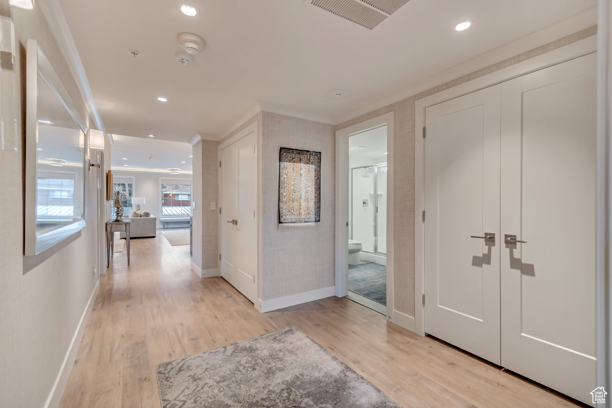 Hallway featuring recessed lighting, visible vents, ornamental molding, and light wood-style flooring