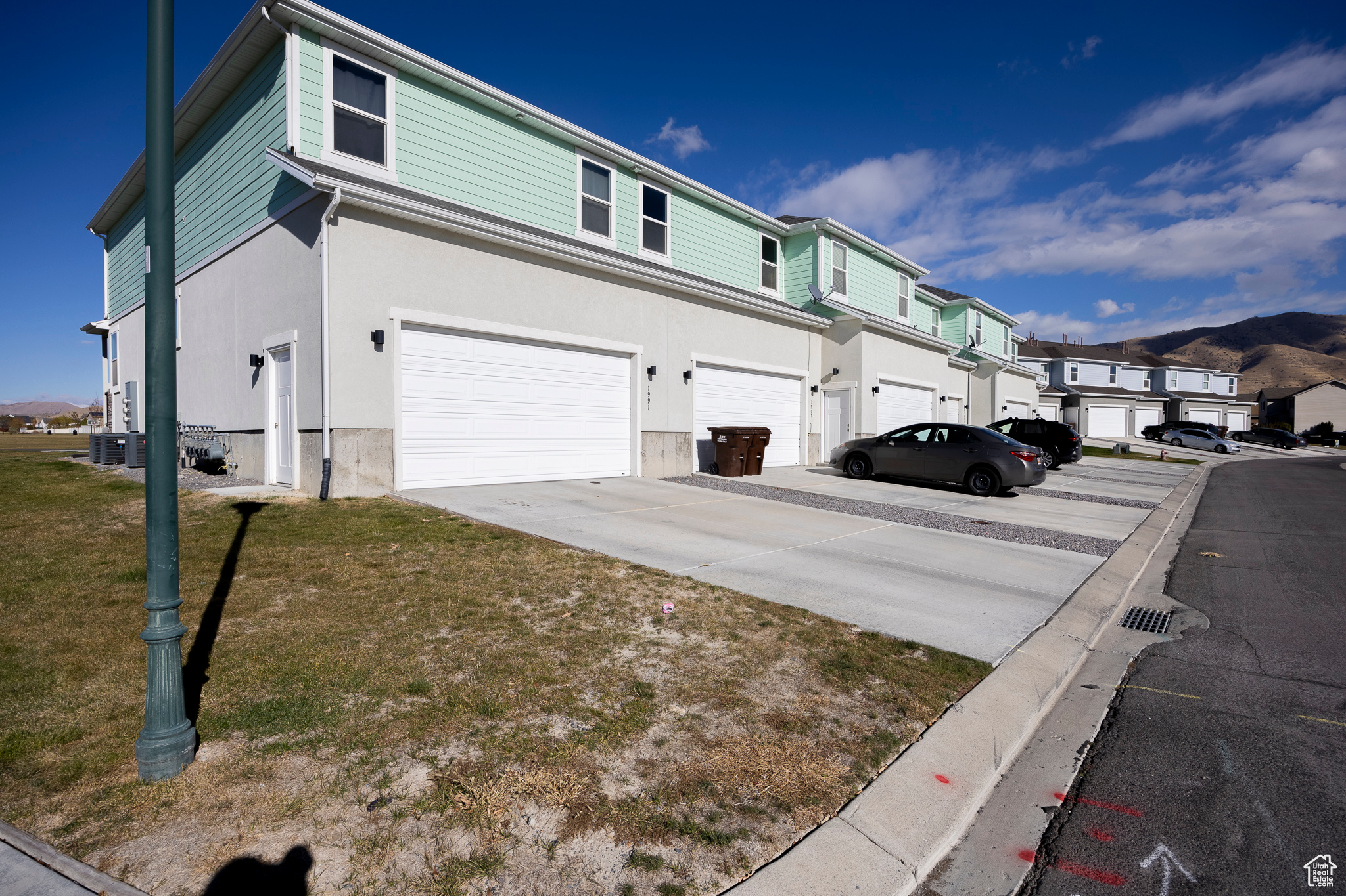 View of side of home featuring driveway, a yard, an attached garage, stucco siding, and a residential view