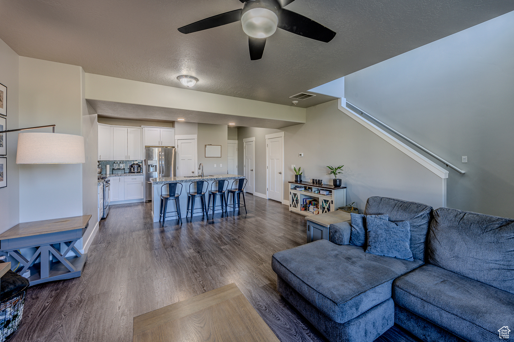 Living room with ceiling fan, dark wood-type flooring, visible vents, and a textured ceiling