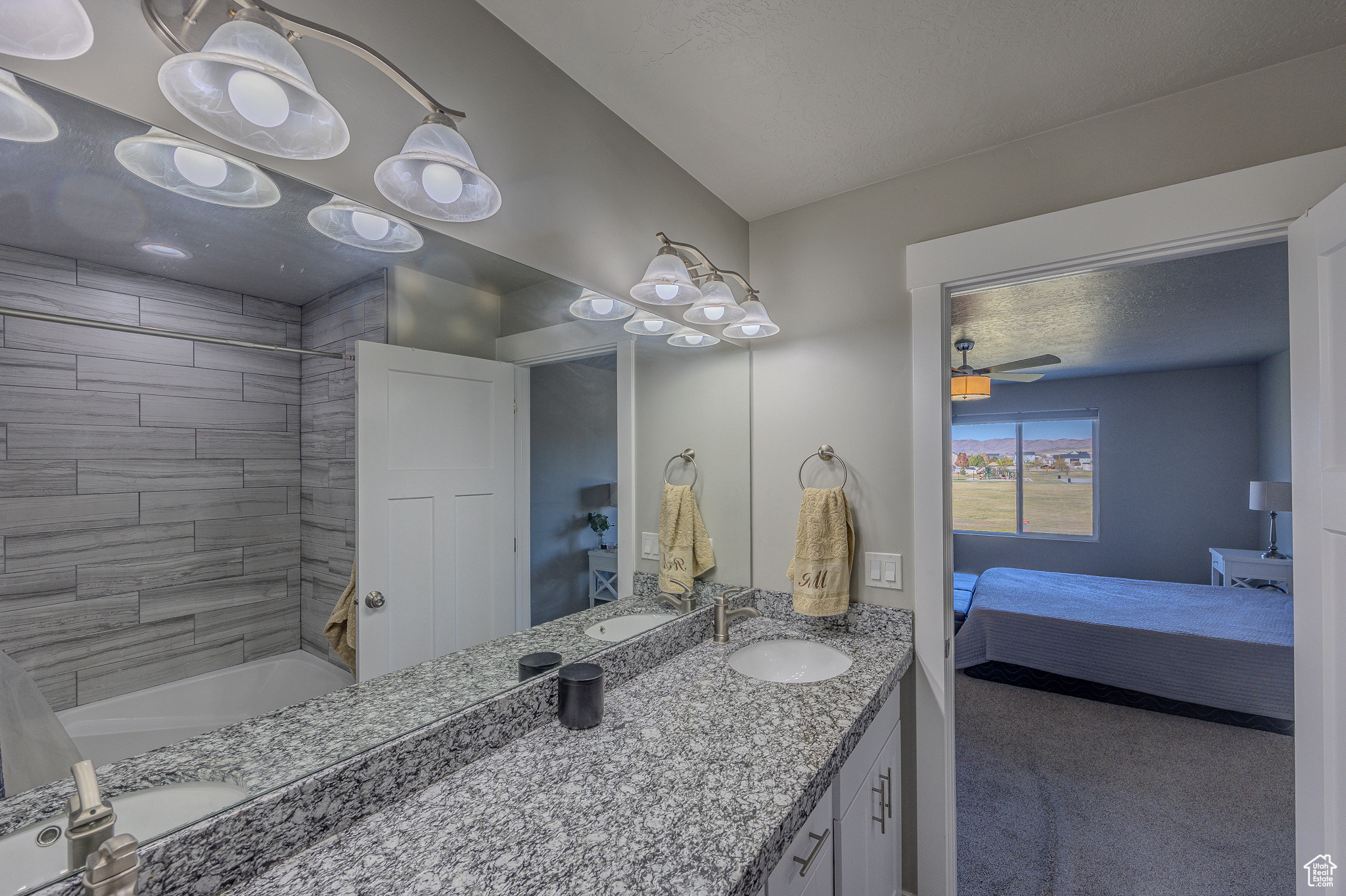 Ensuite bathroom with vanity, a ceiling fan, ensuite bathroom, a textured ceiling, and shower / bathing tub combination