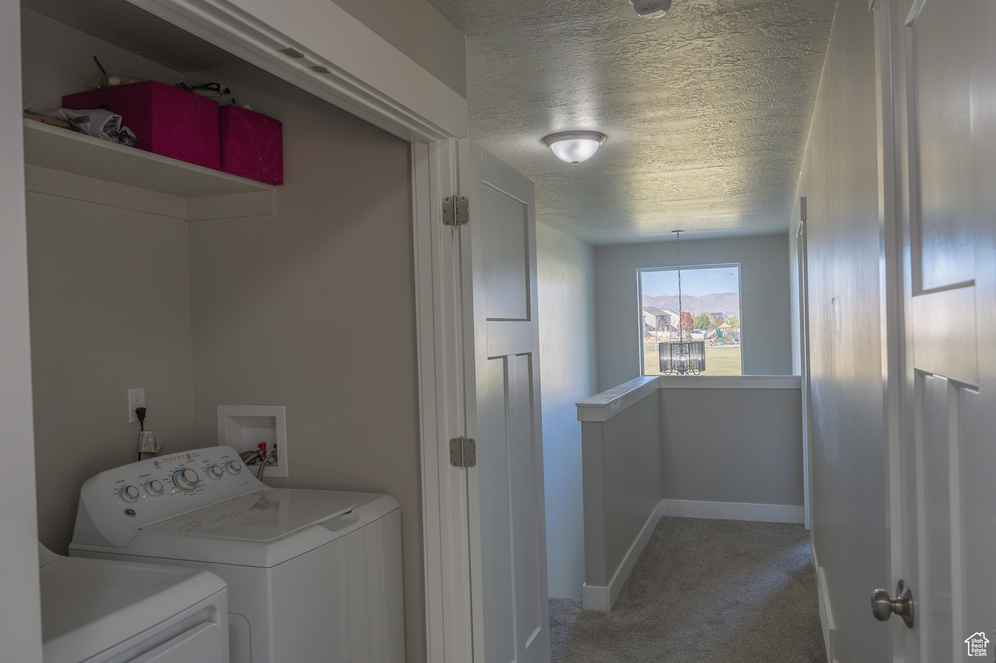 Laundry room with light carpet, washer and dryer, a textured ceiling, baseboards, and laundry area