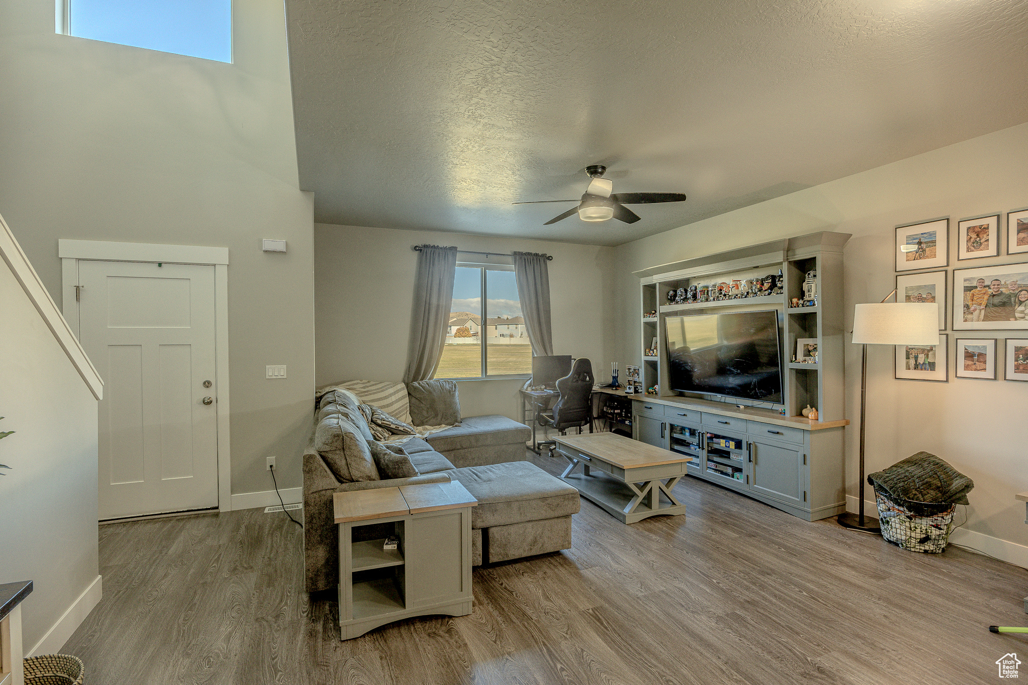 Living area with baseboards, a textured ceiling, wood finished floors, and a ceiling fan