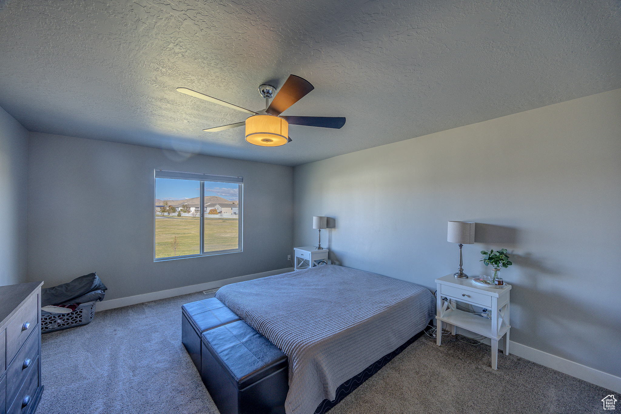 Carpeted bedroom with a ceiling fan, baseboards, and a textured ceiling