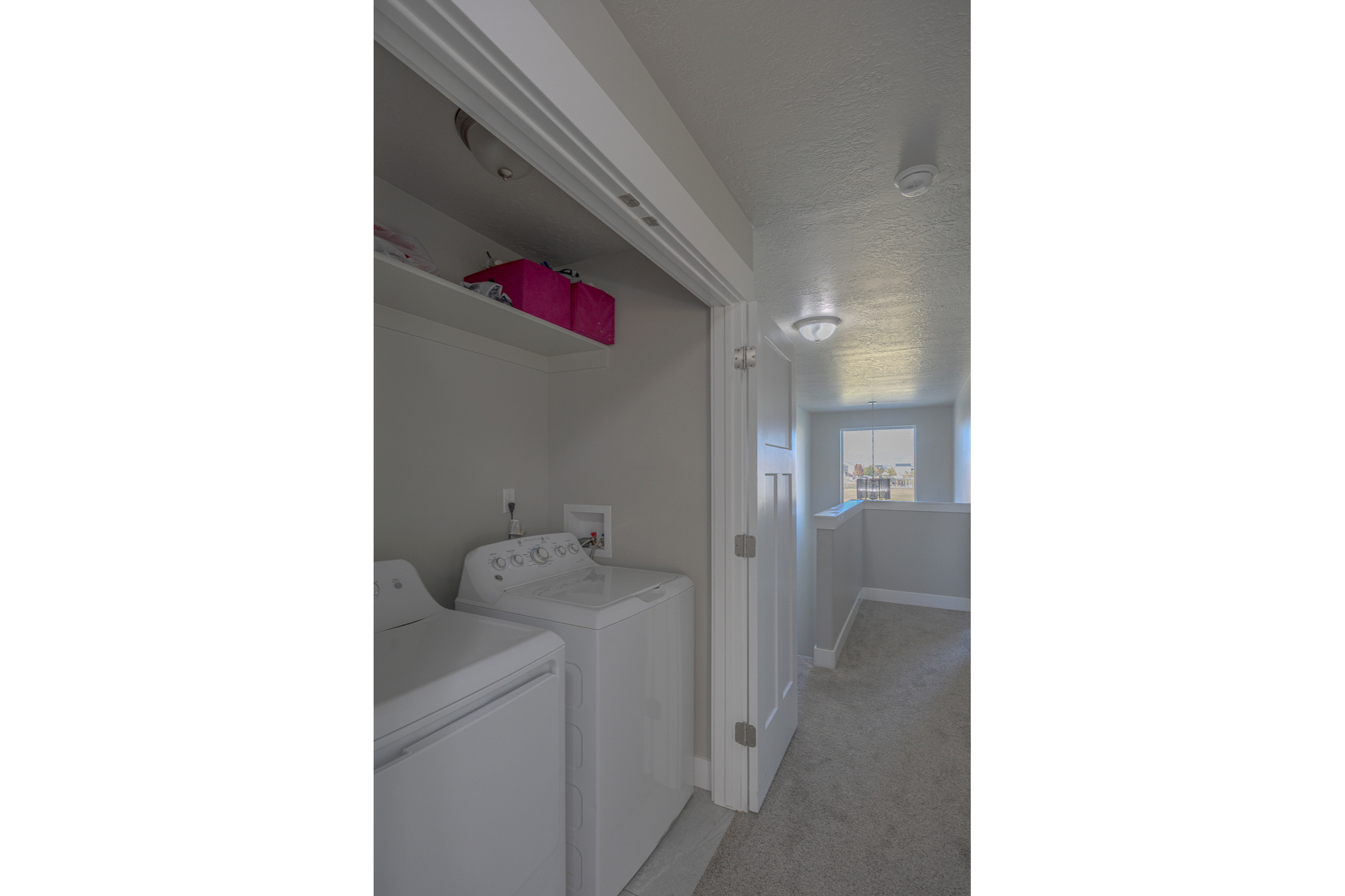 Washroom with baseboards, laundry area, separate washer and dryer, a textured ceiling, and light colored carpet