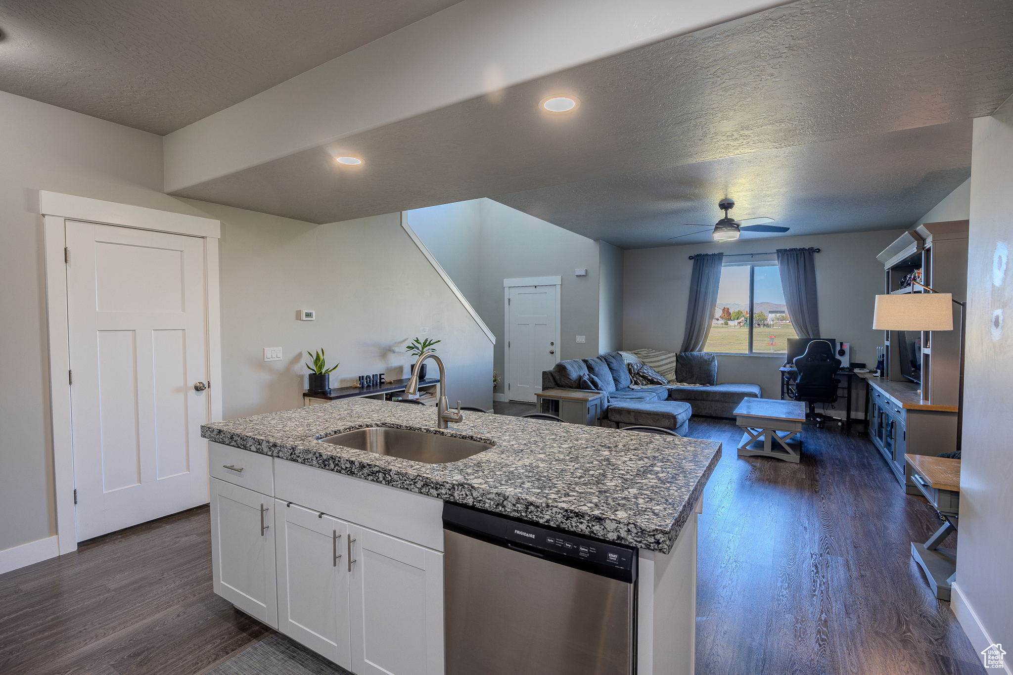 Kitchen with an island with sink, a sink, dark wood-style floors, white cabinetry, and dishwasher