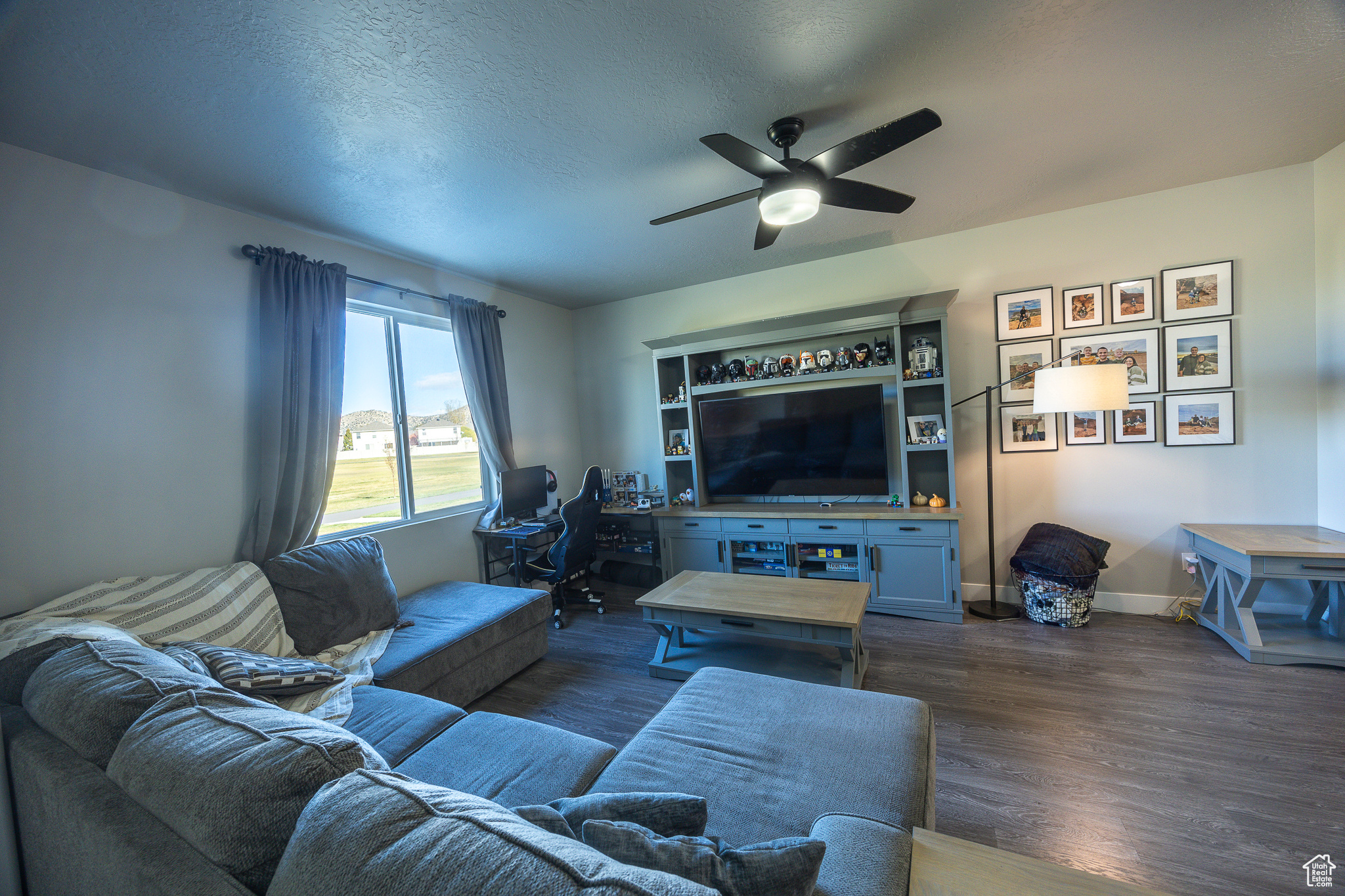 Living room featuring dark wood finished floors, a ceiling fan, baseboards, and a textured ceiling