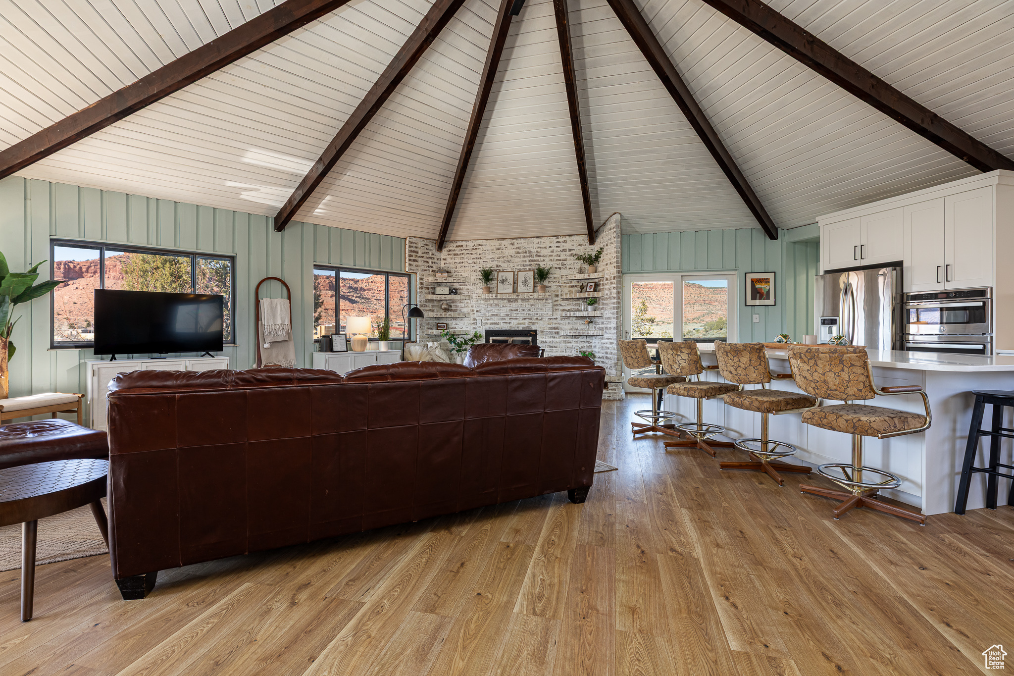 Living room featuring light wood-type flooring, a fireplace, and vaulted ceiling with beams