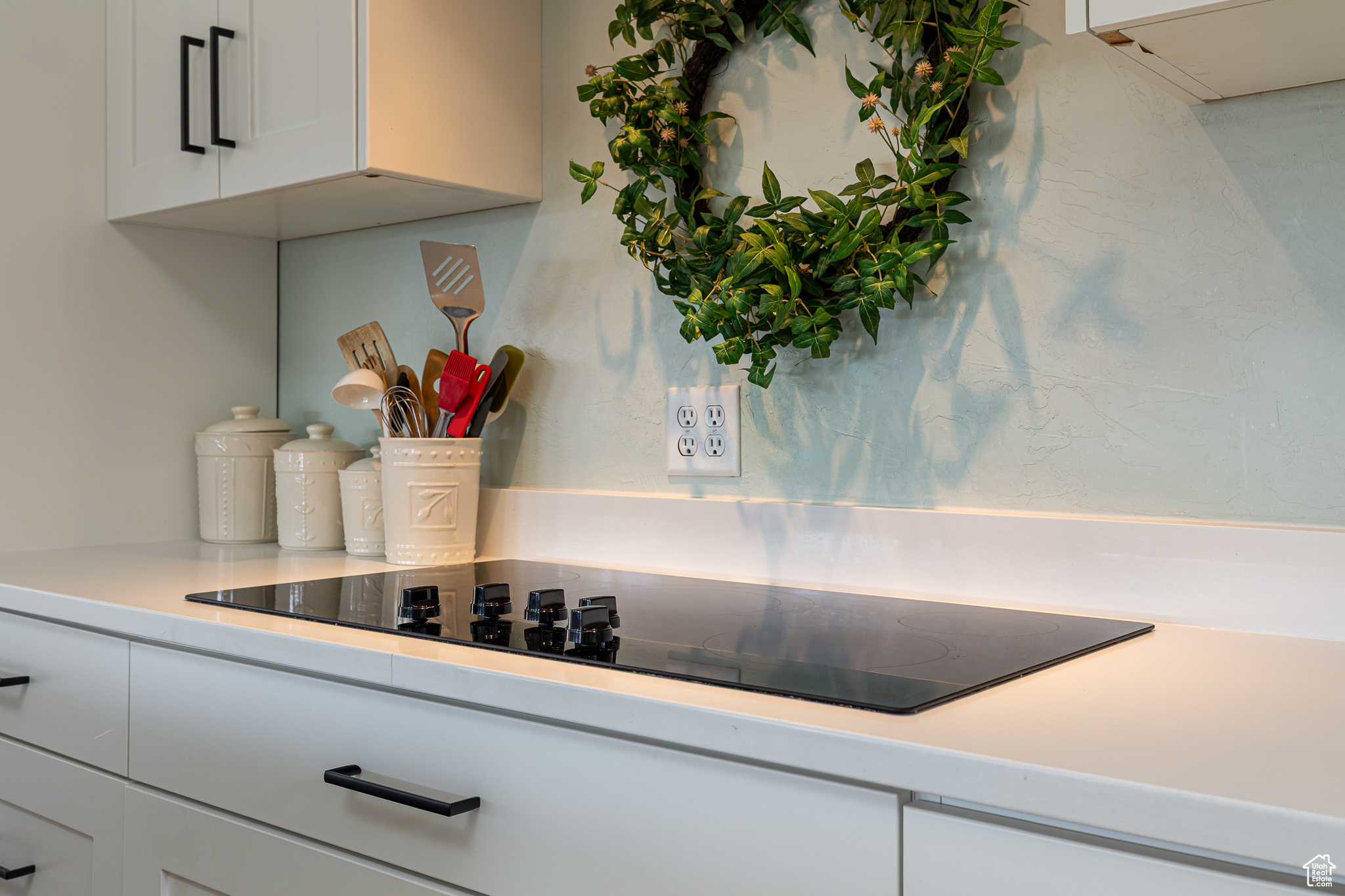 Details featuring white cabinetry, light countertops, and black electric cooktop