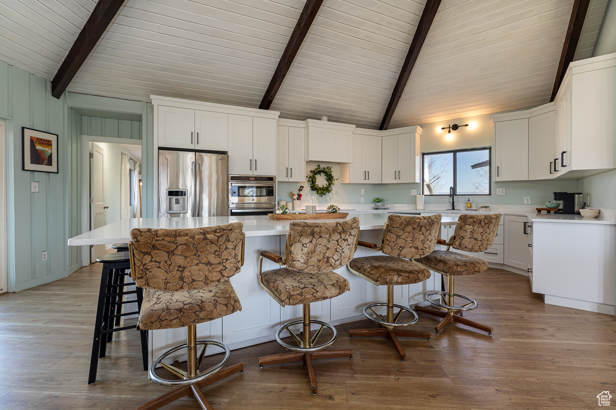 Kitchen with a kitchen island, white cabinetry, stainless steel appliances, and light wood-style floors