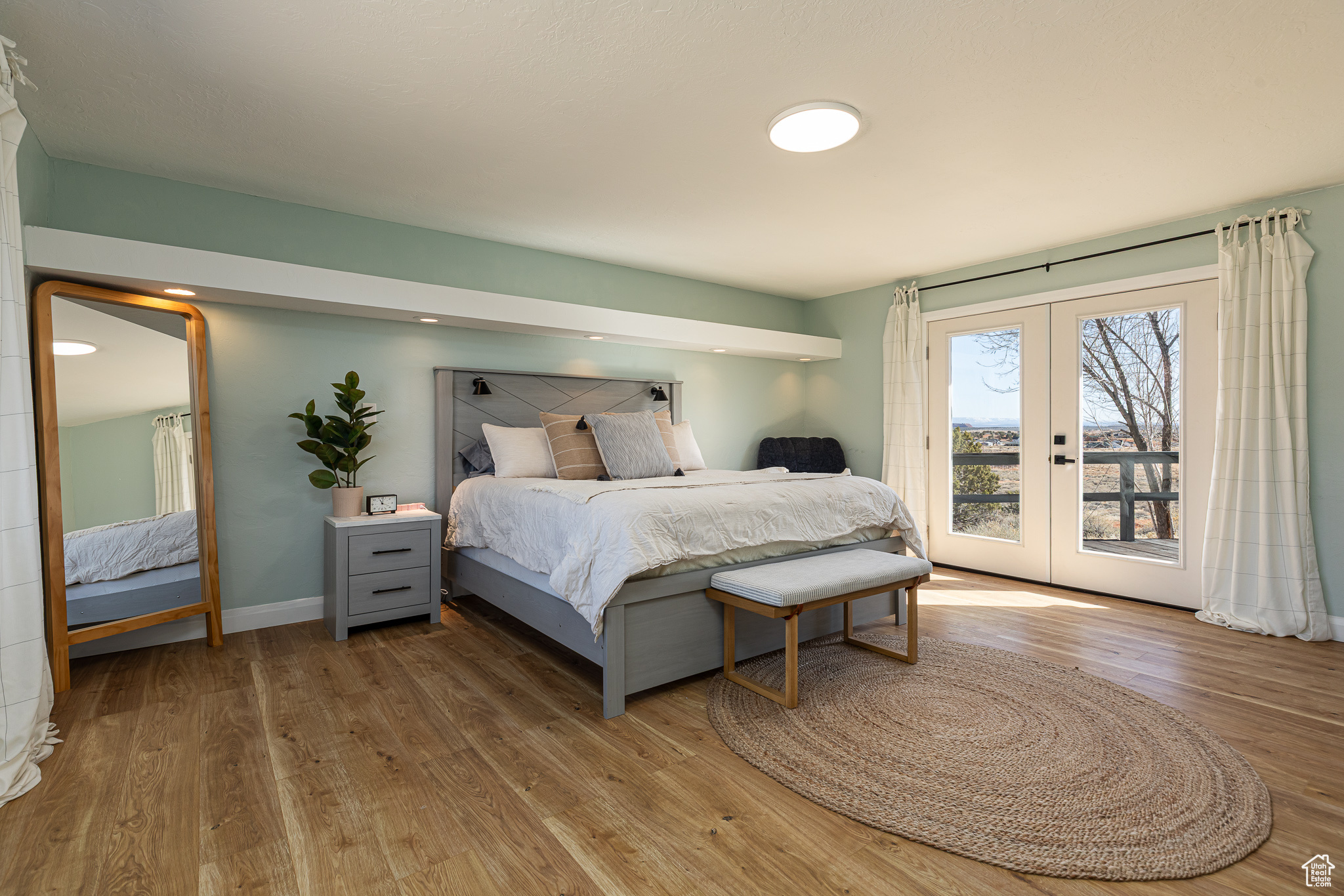 Bedroom featuring access to exterior, french doors, baseboards, and wood finished floors