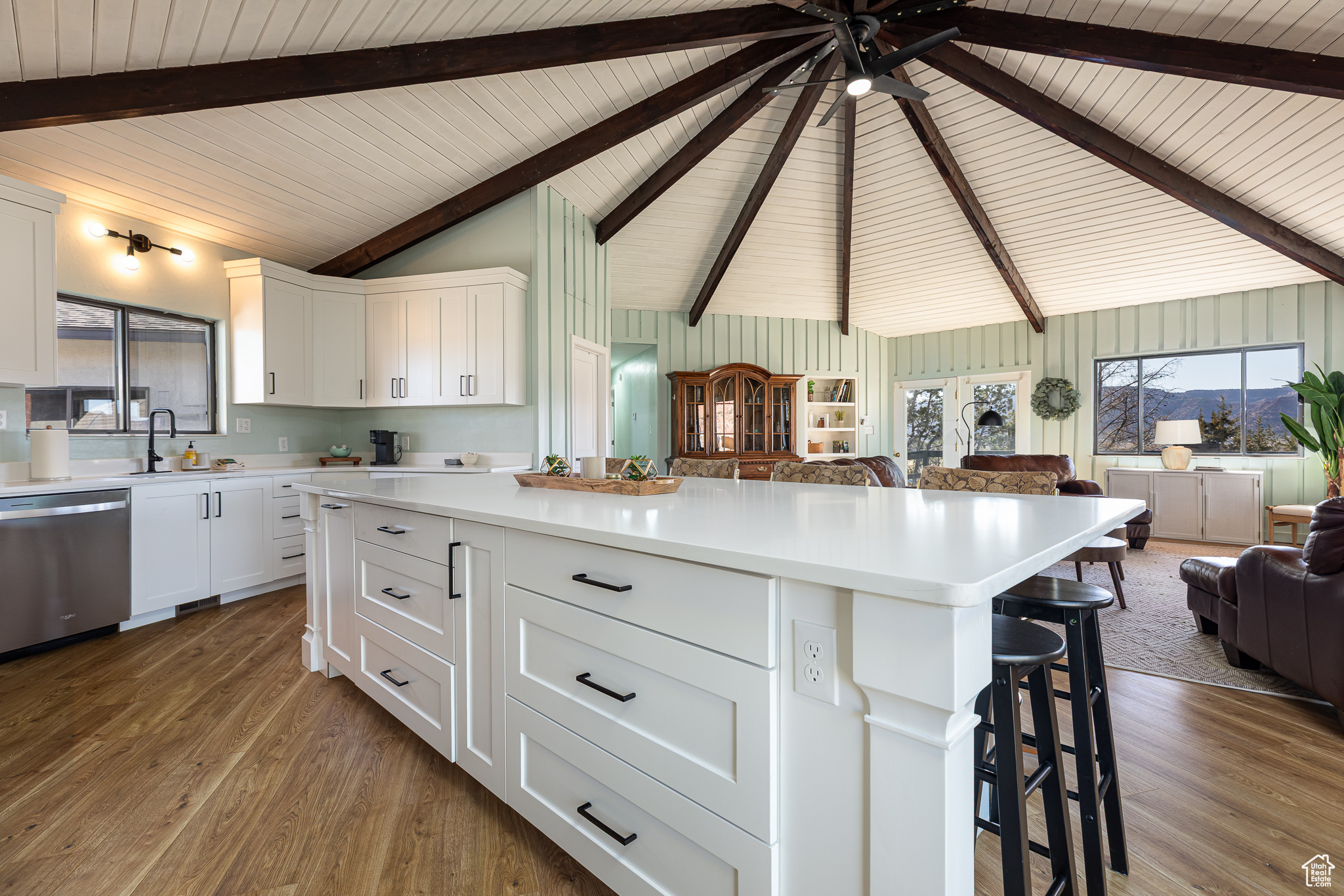 Kitchen featuring stainless steel dishwasher, wood finished floors, open floor plan, a breakfast bar area, and vaulted ceiling with beams