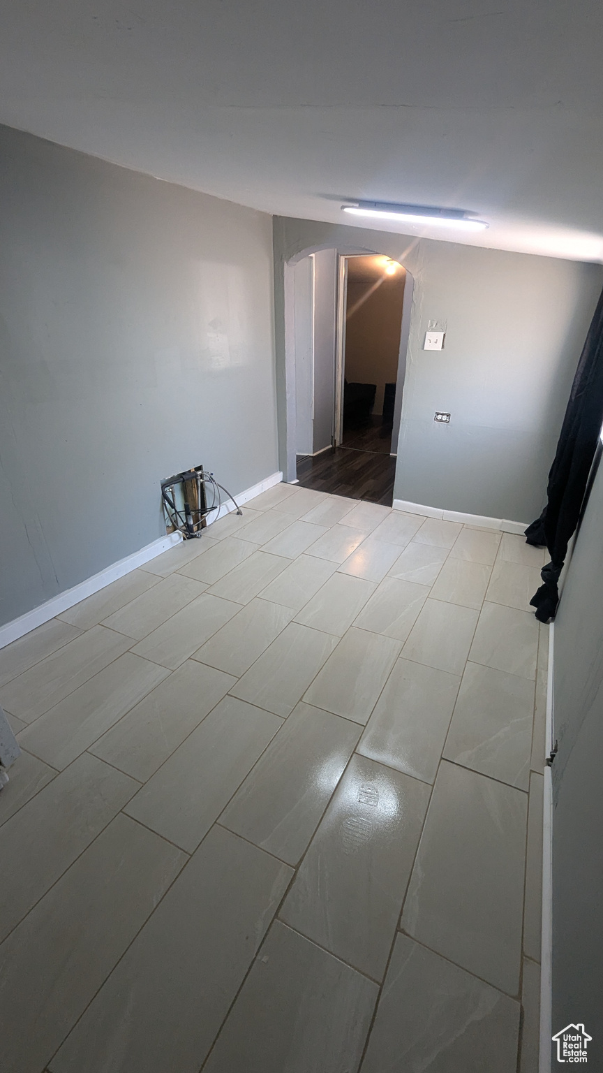 Unfurnished room with arched walkways and baseboards