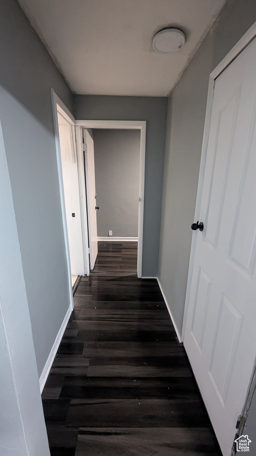 Hallway featuring baseboards and dark wood finished floors