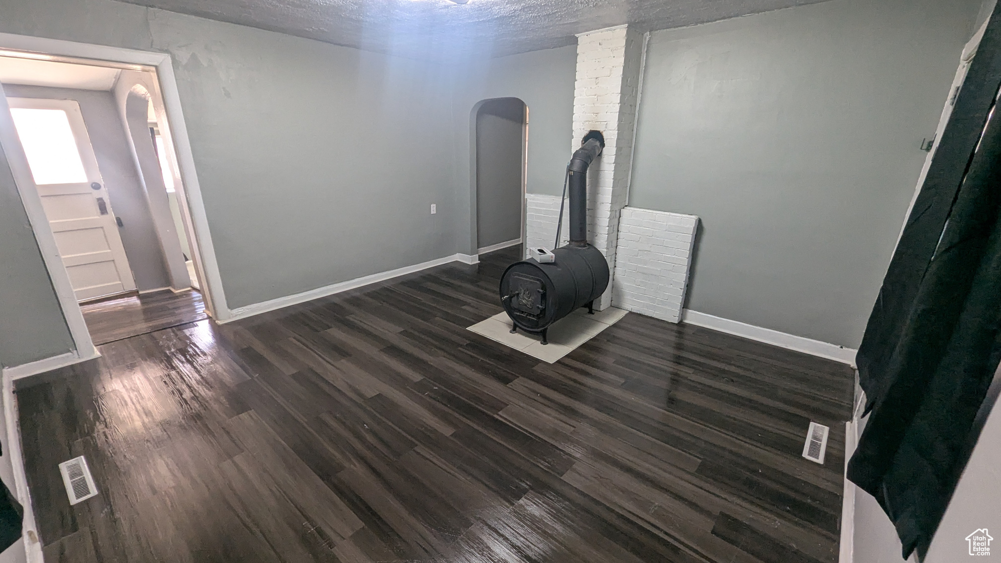 Interior space featuring arched walkways, visible vents, dark wood-type flooring, and baseboards