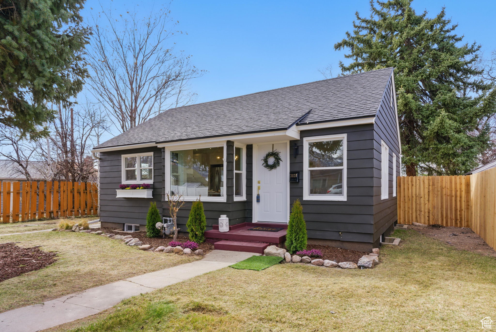 Bungalow-style home featuring roof with shingles, a fenced backyard, and a front yard