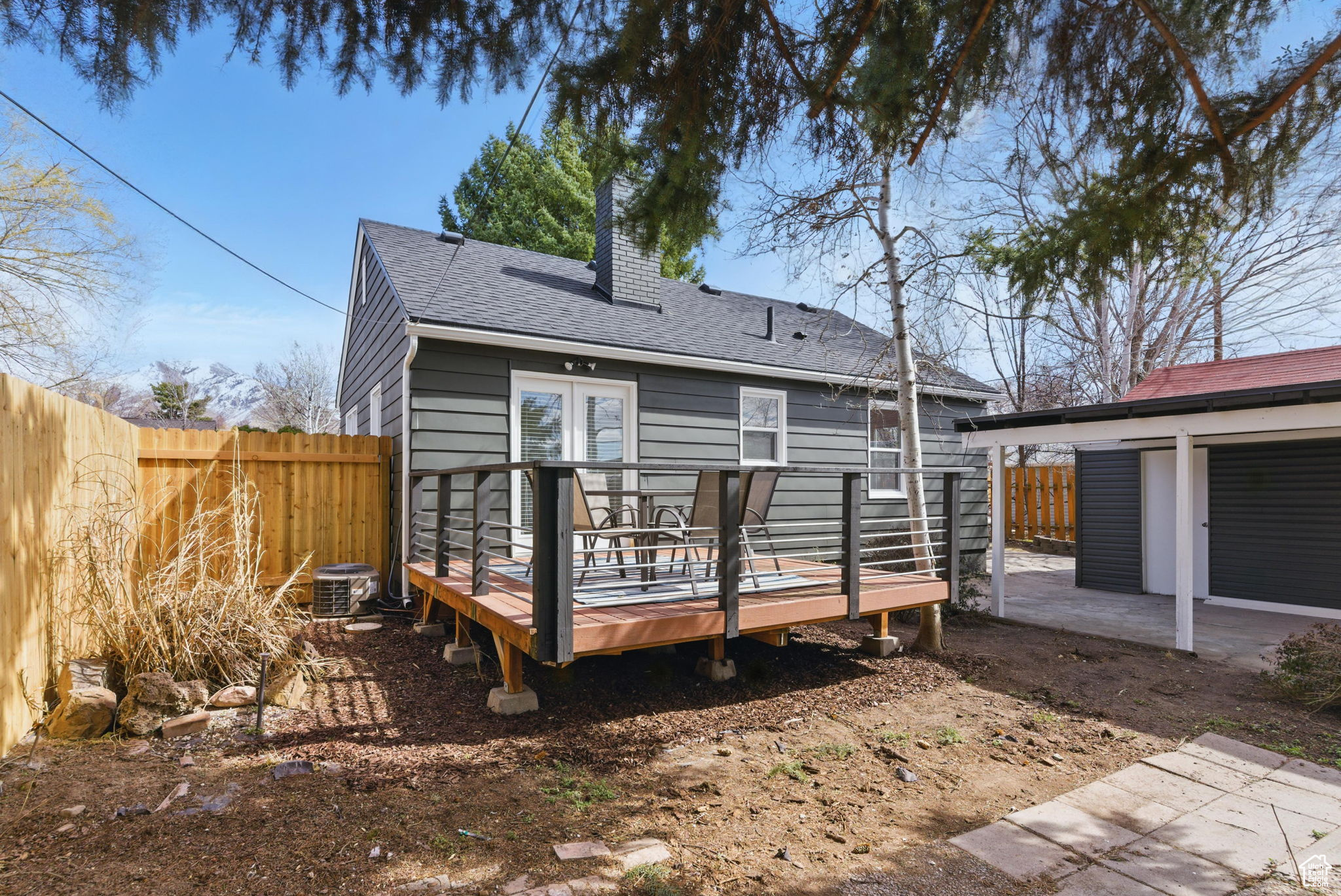 Back of house featuring a deck, a fenced backyard, roof with shingles, and a chimney