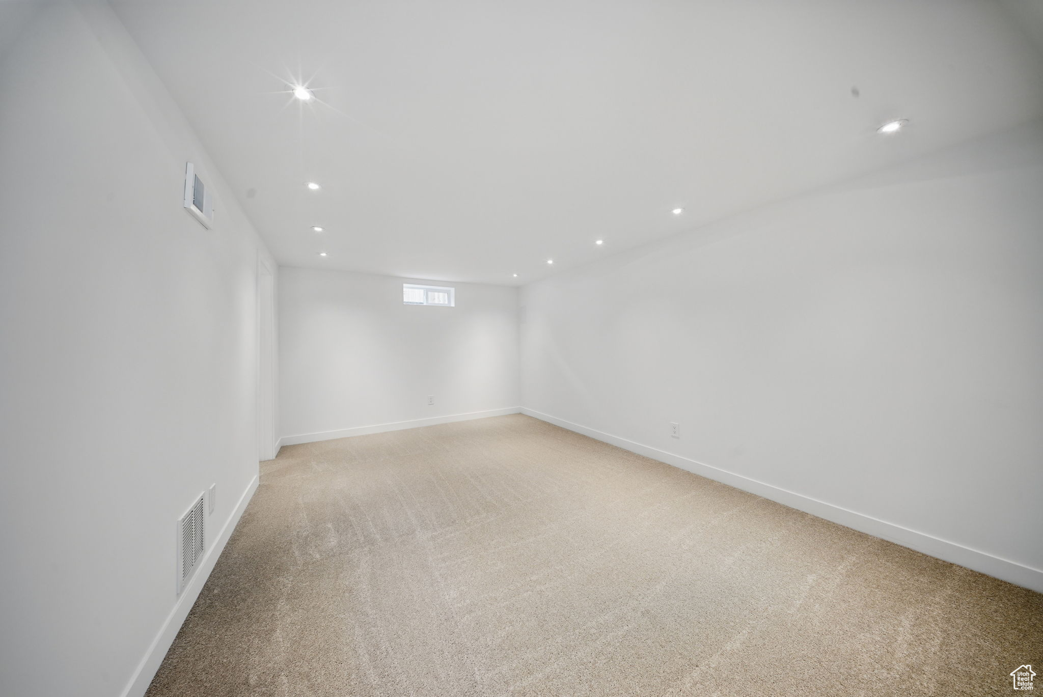 Below grade area featuring recessed lighting, visible vents, baseboards, and light colored carpet