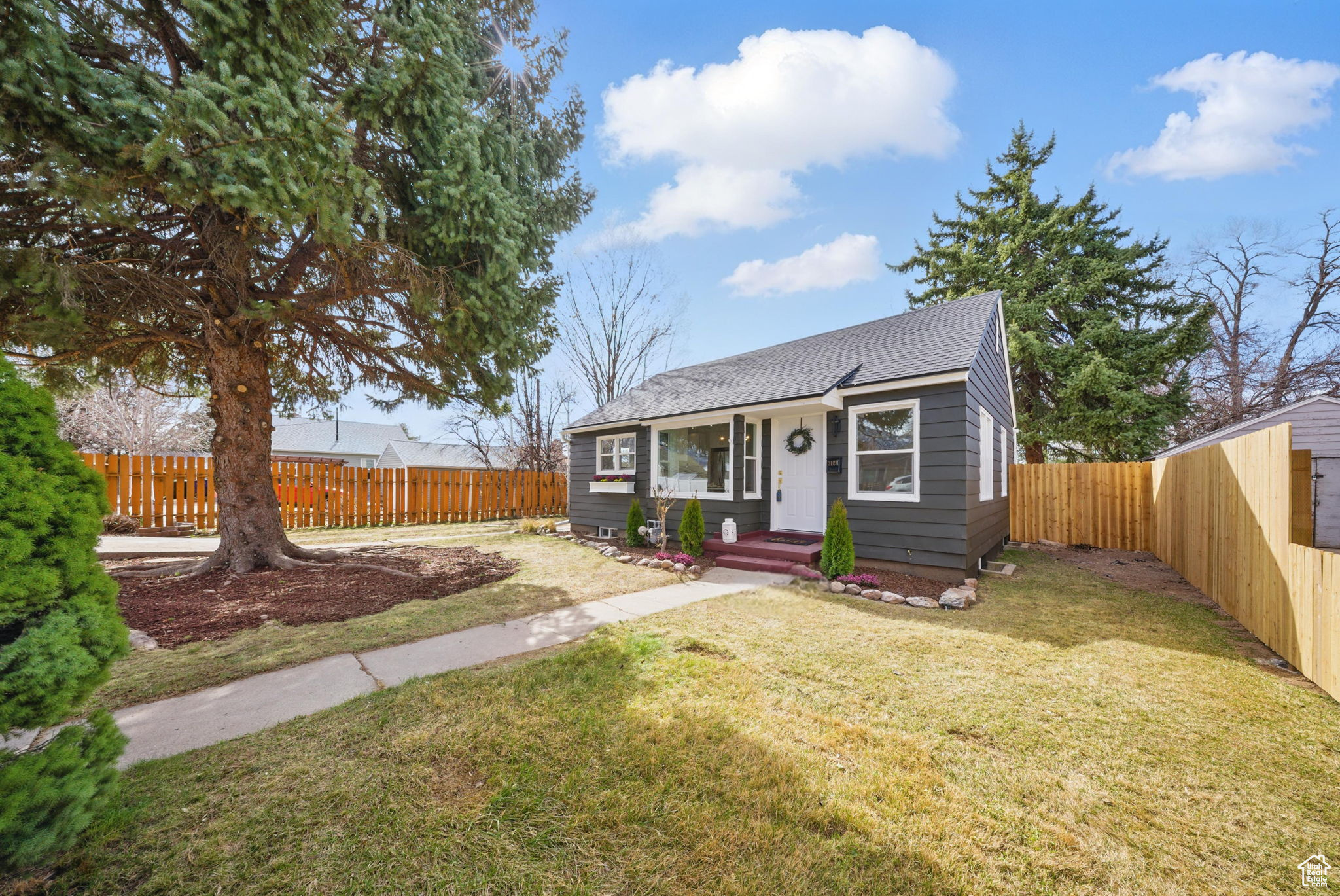 Bungalow-style home with a front yard, a fenced backyard, and a shingled roof