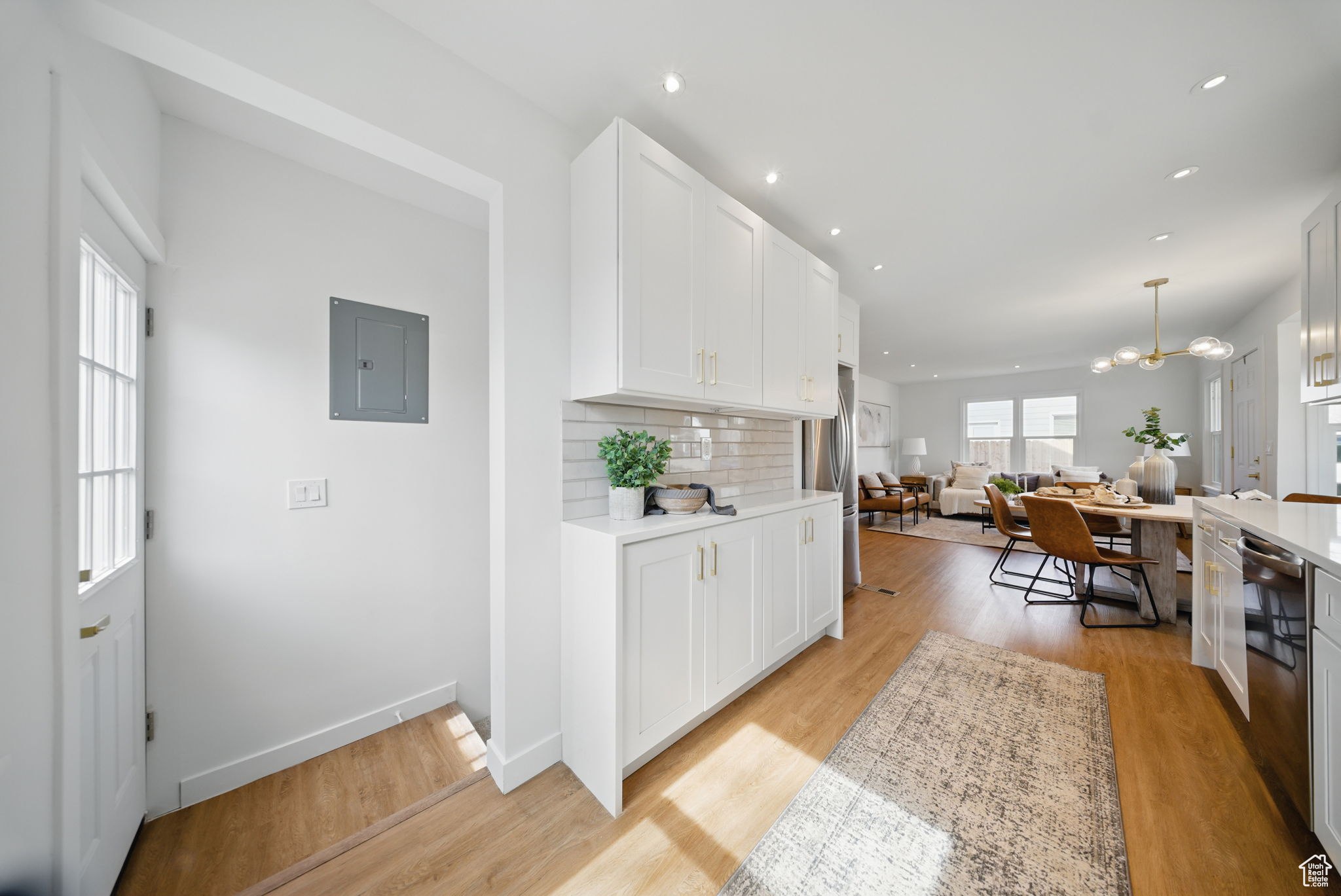 Kitchen with light wood-type flooring, electric panel, open floor plan, light countertops, and decorative backsplash