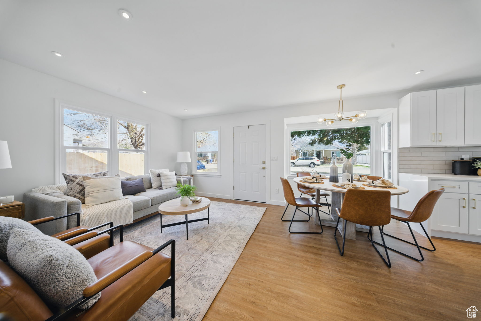 Living area with a notable chandelier, recessed lighting, baseboards, and light wood-style floors