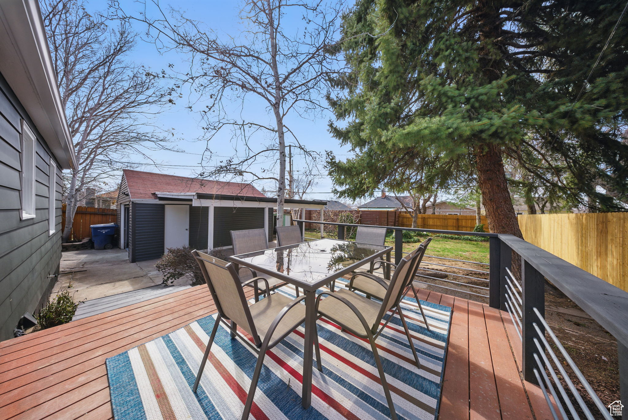 Wooden terrace with outdoor dining area, an outbuilding, and a fenced backyard