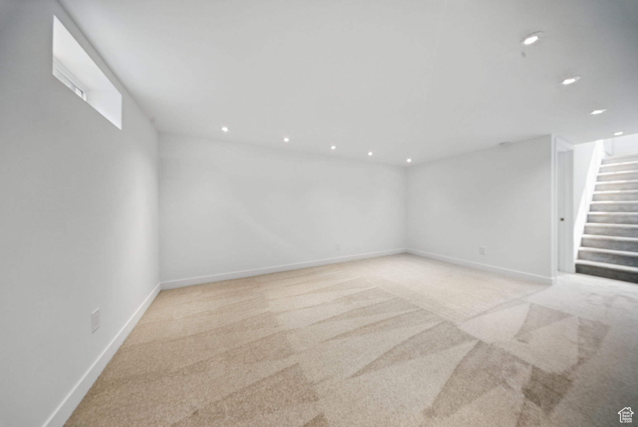 Unfurnished room with light carpet, recessed lighting, stairs, and baseboards