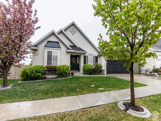 View of front facade with fence, a front yard, stucco siding, a garage, and driveway