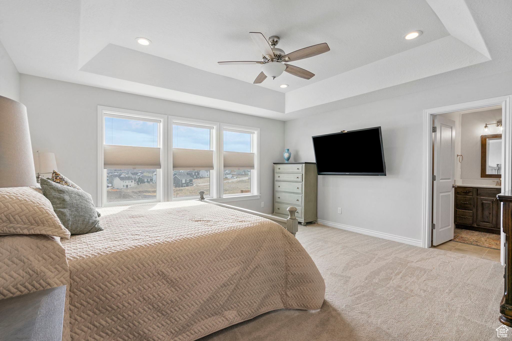 Bedroom with a raised ceiling, recessed lighting, baseboards, and light carpet