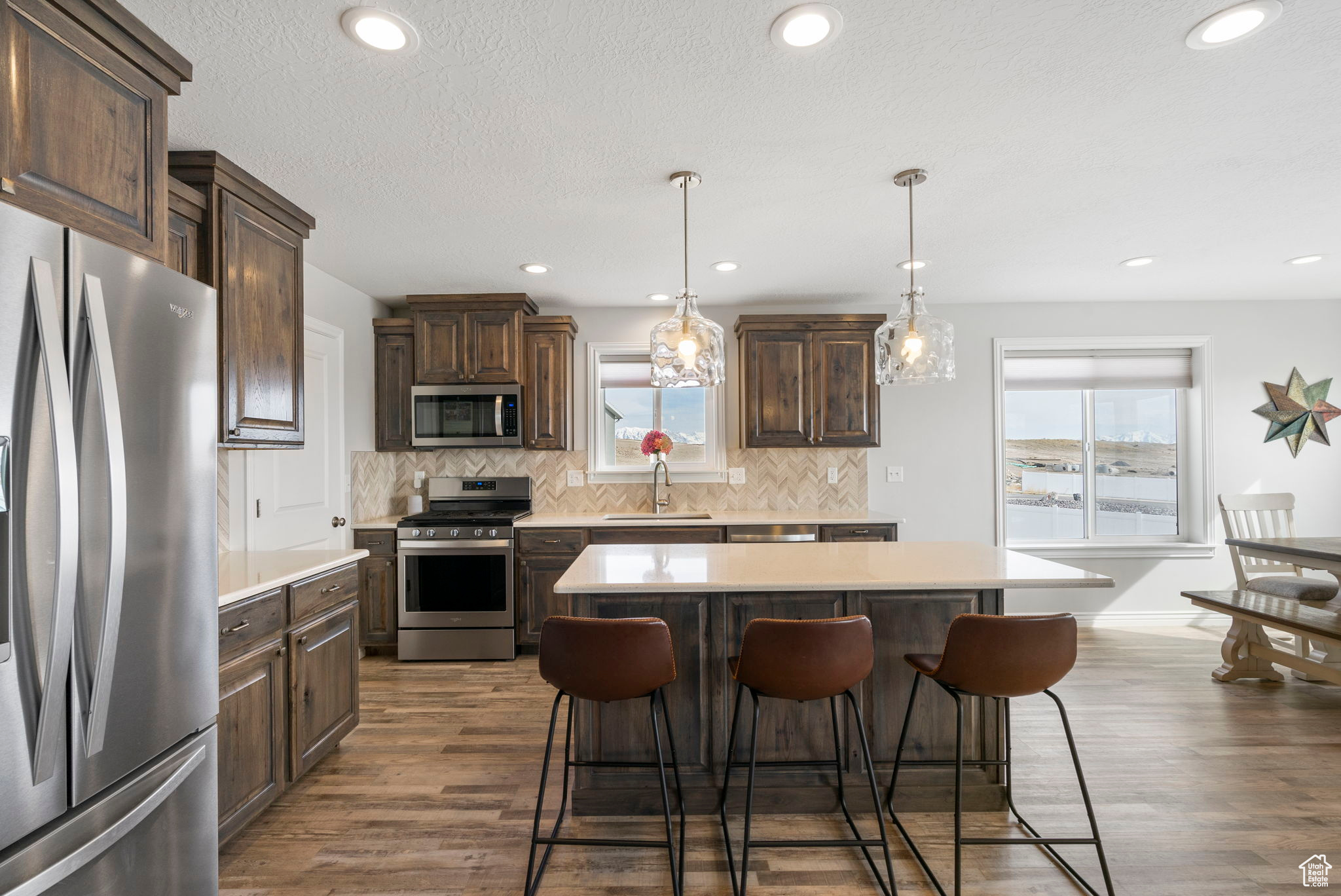 Kitchen featuring dark brown cabinets, appliances with stainless steel finishes, a kitchen breakfast bar, and a sink