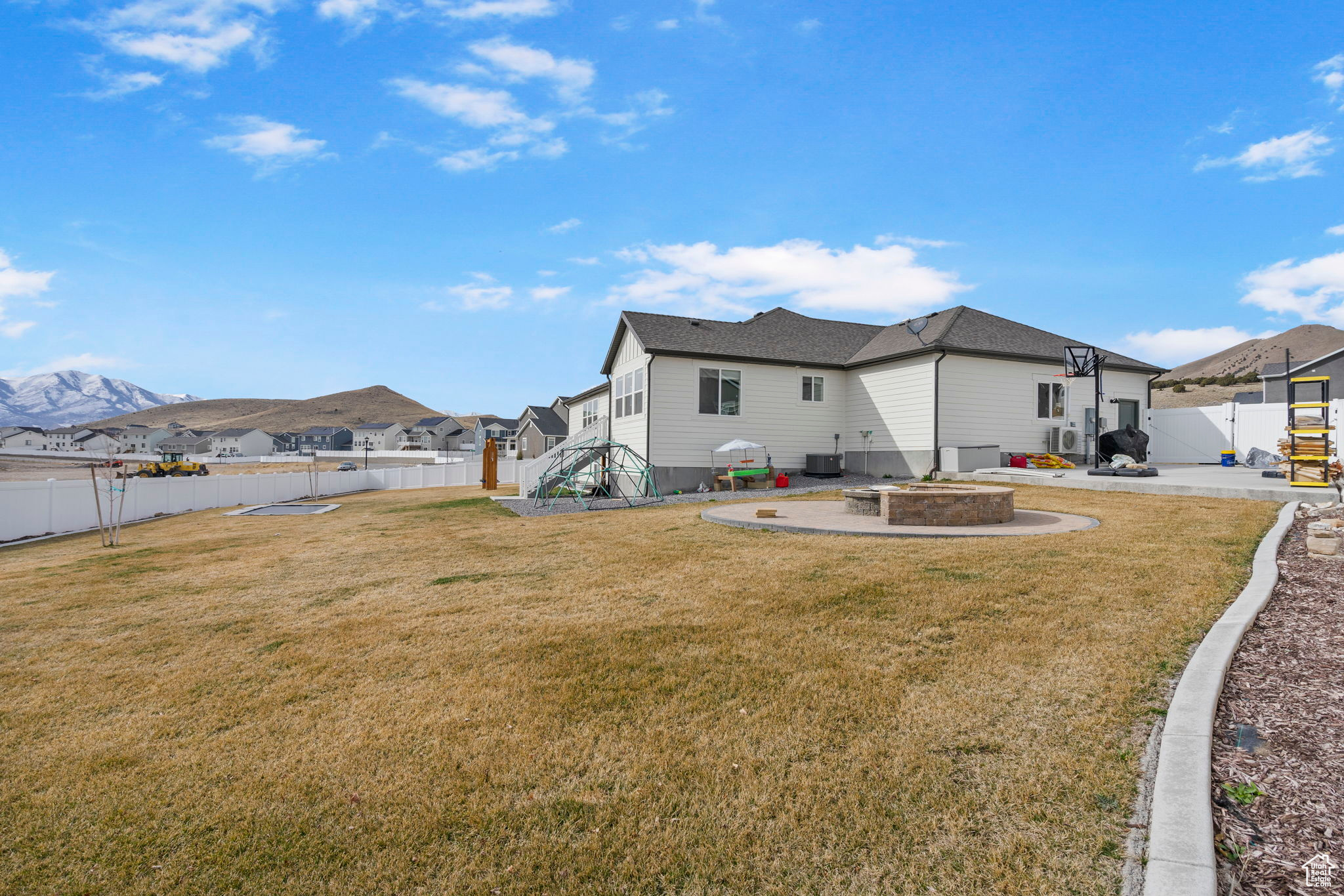 Exterior space featuring a patio, central AC unit, a yard, a fenced backyard, and a mountain view