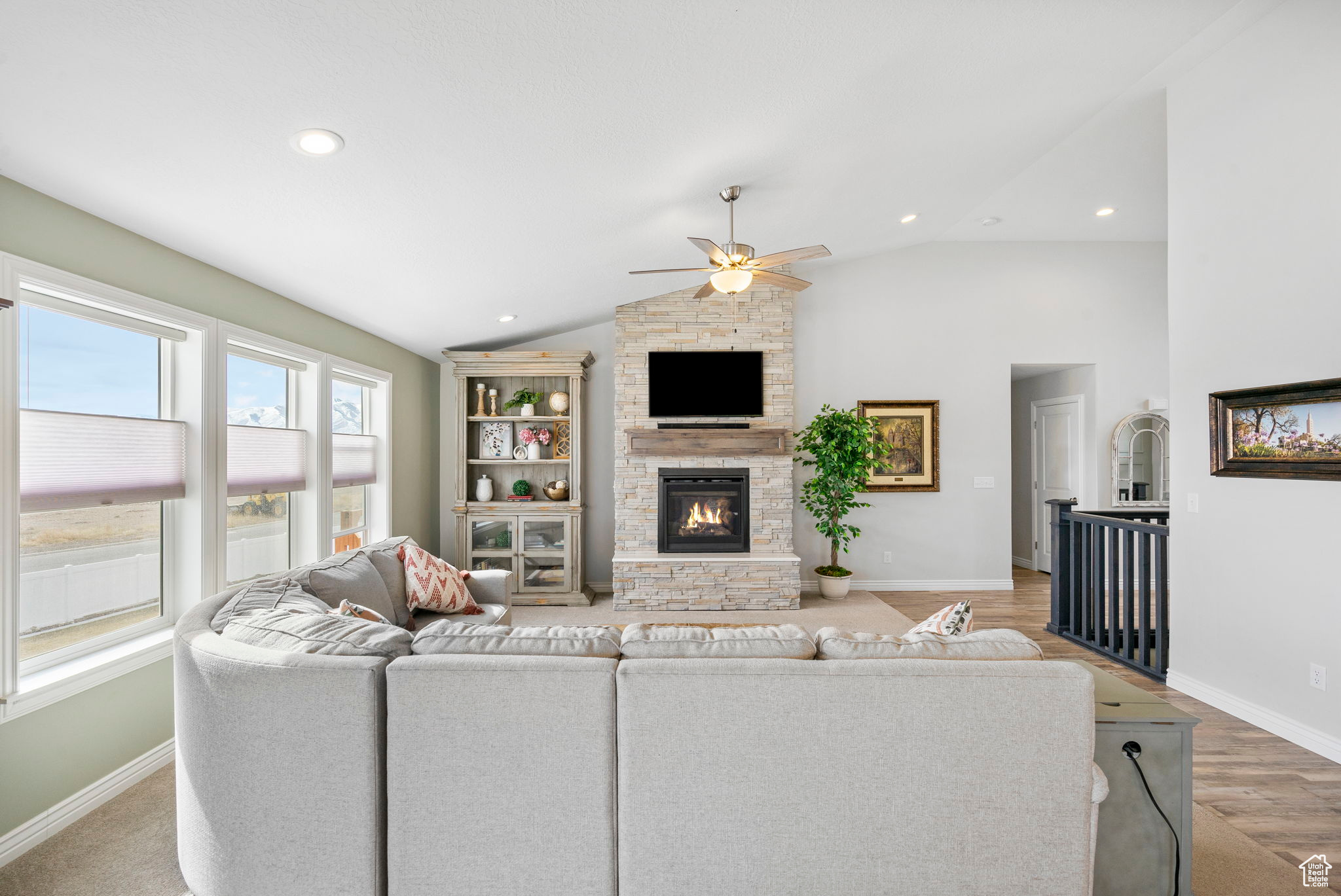 Living room featuring a stone fireplace, vaulted ceiling, recessed lighting, and baseboards