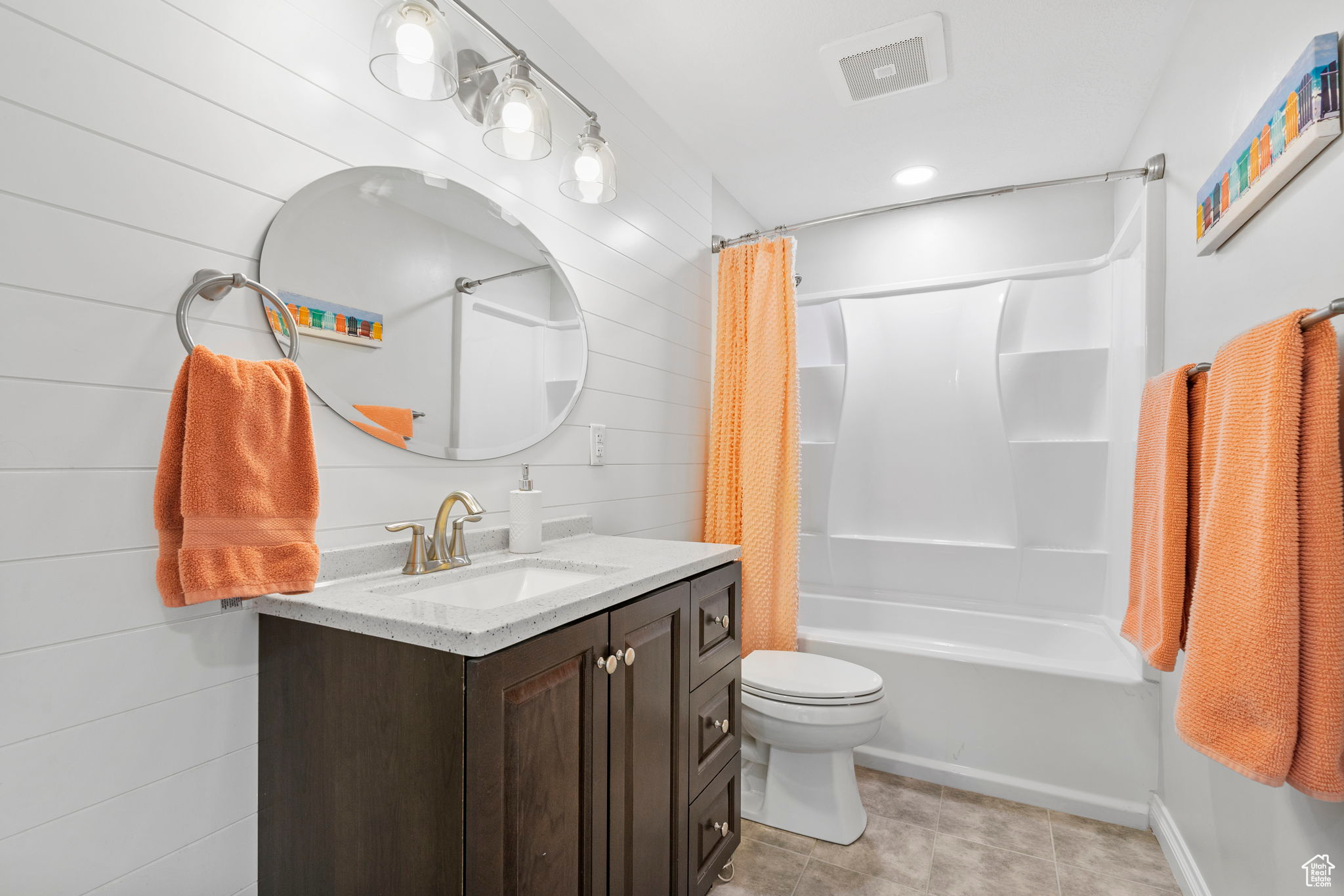 Full bathroom featuring vanity, tile patterned flooring, shower / tub combo, wood walls, and toilet