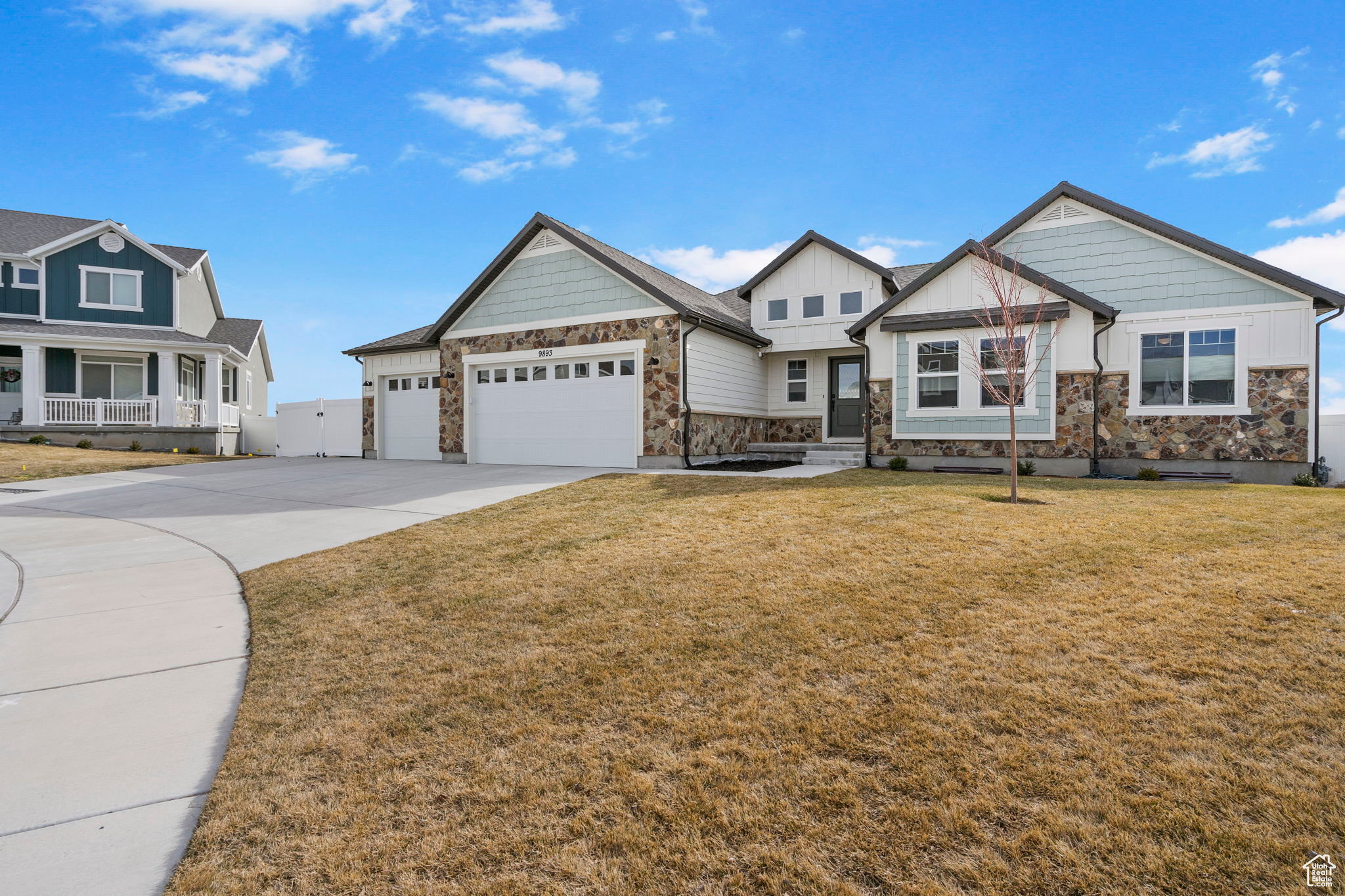 View of front of house with a front lawn, a garage, stone siding, and driveway