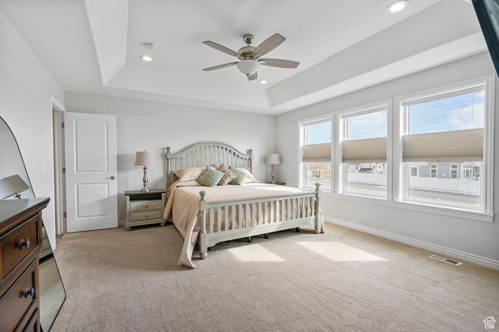 Bedroom with visible vents, baseboards, light colored carpet, a tray ceiling, and recessed lighting