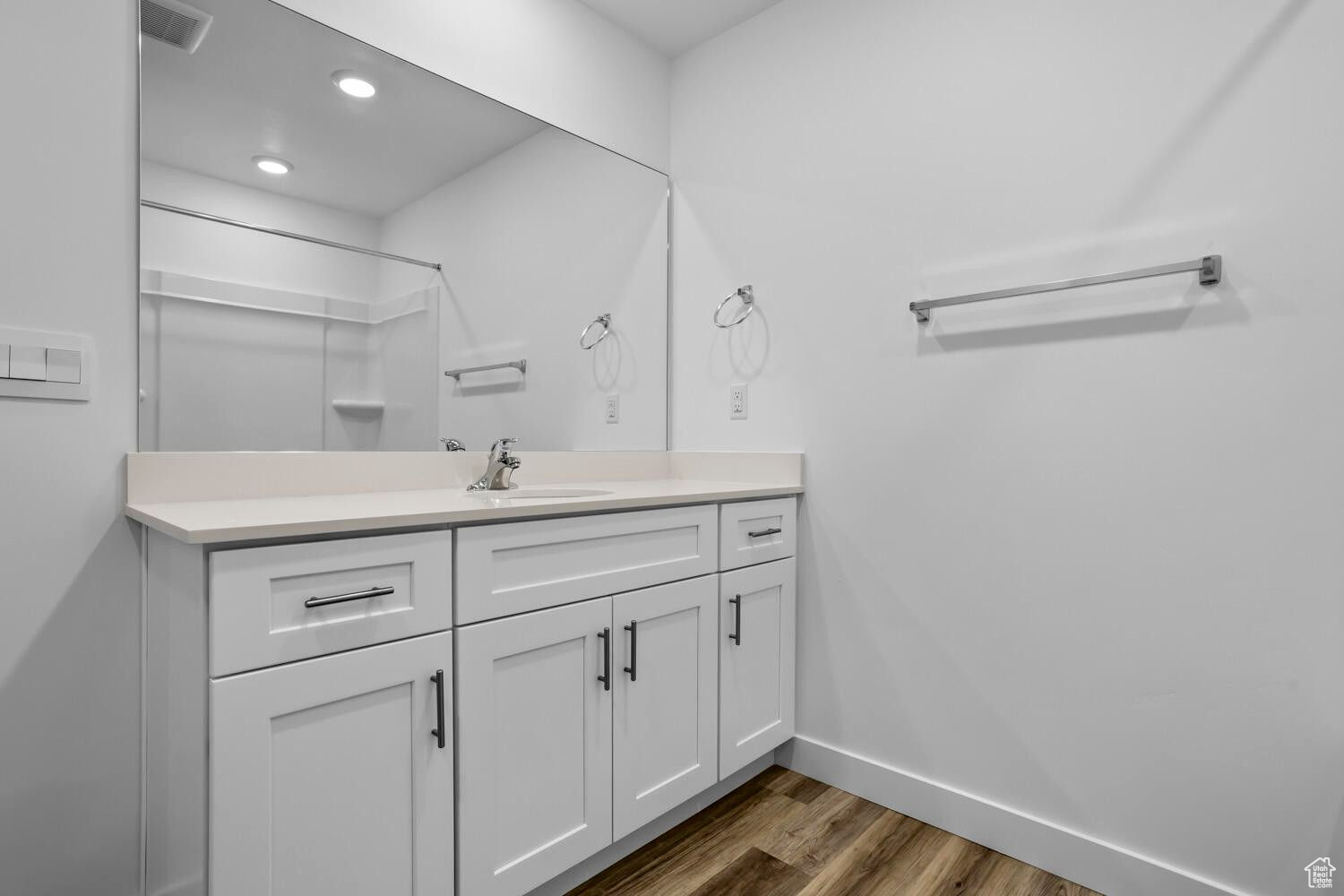 Bathroom featuring visible vents, baseboards, recessed lighting, wood finished floors, and vanity