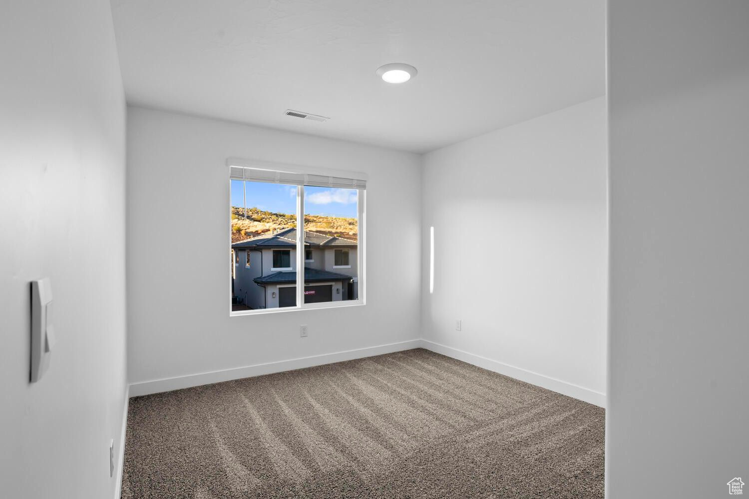 Carpeted spare room with visible vents and baseboards