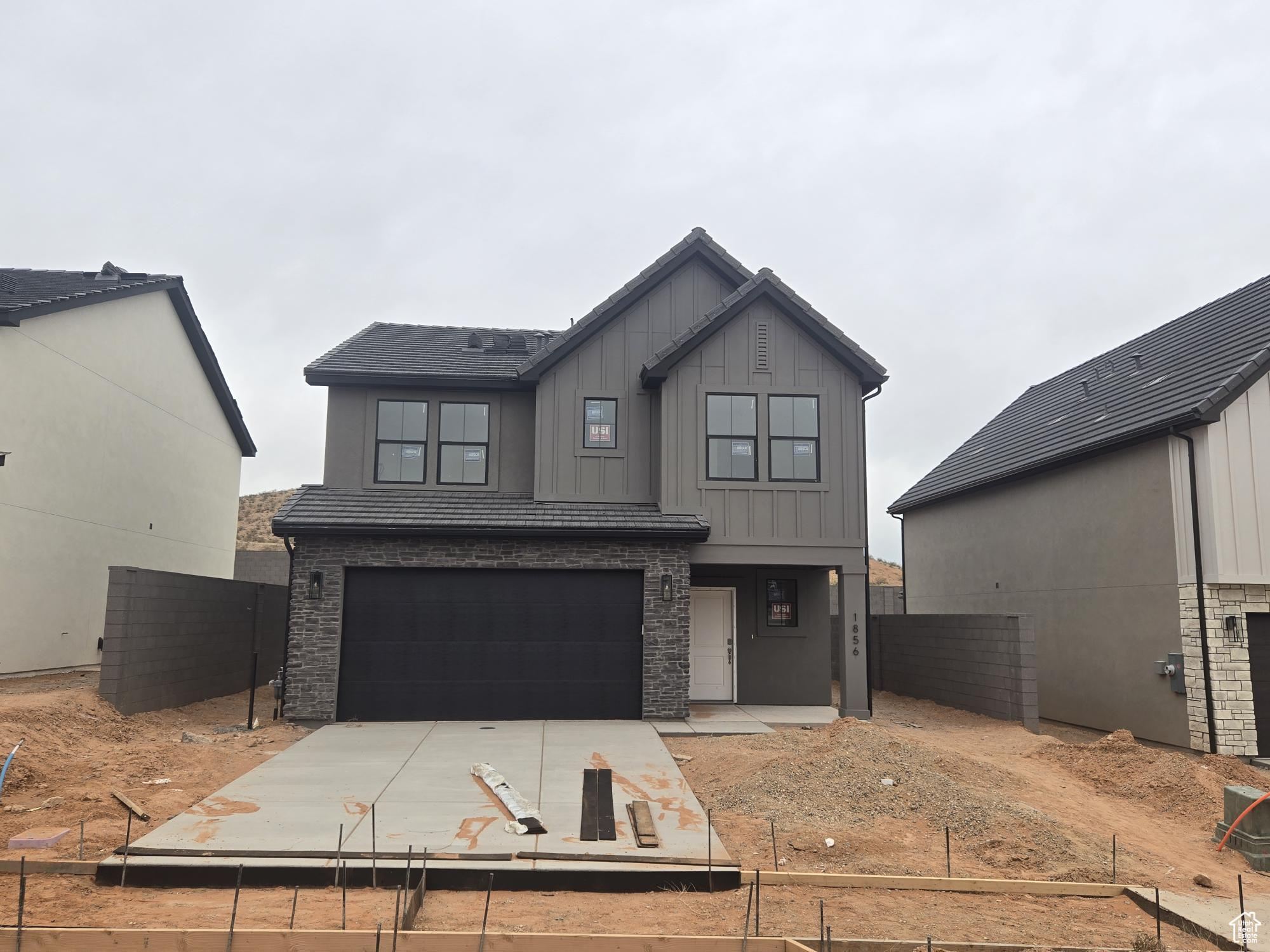 Modern farmhouse featuring board and batten siding, concrete driveway, an attached garage, and fence