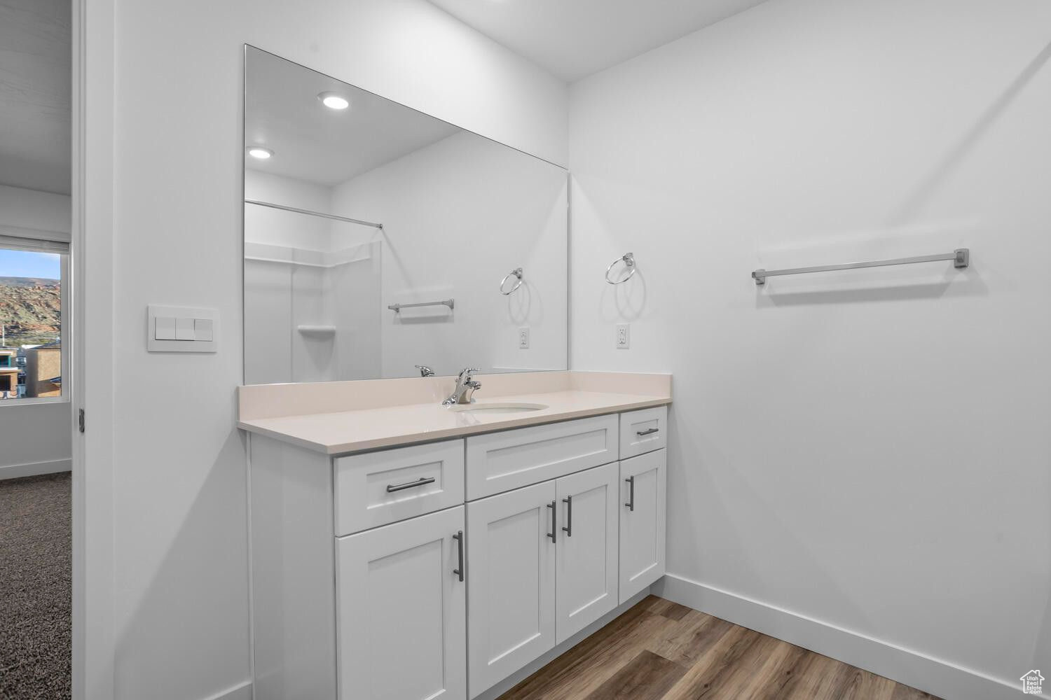 Bathroom featuring walk in shower, baseboards, recessed lighting, wood finished floors, and vanity