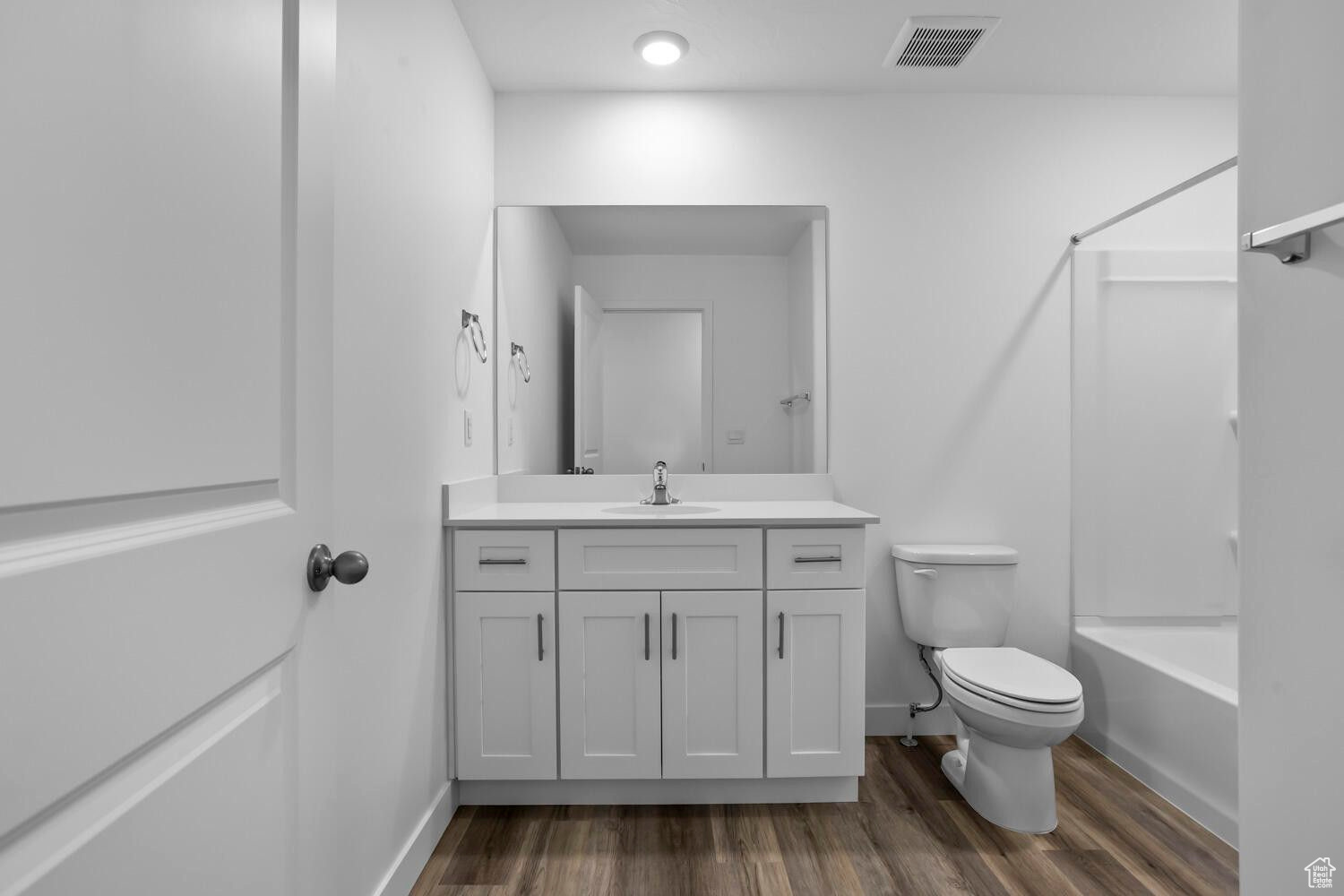 Full bath with visible vents, toilet, shower / tub combination, wood finished floors, and vanity