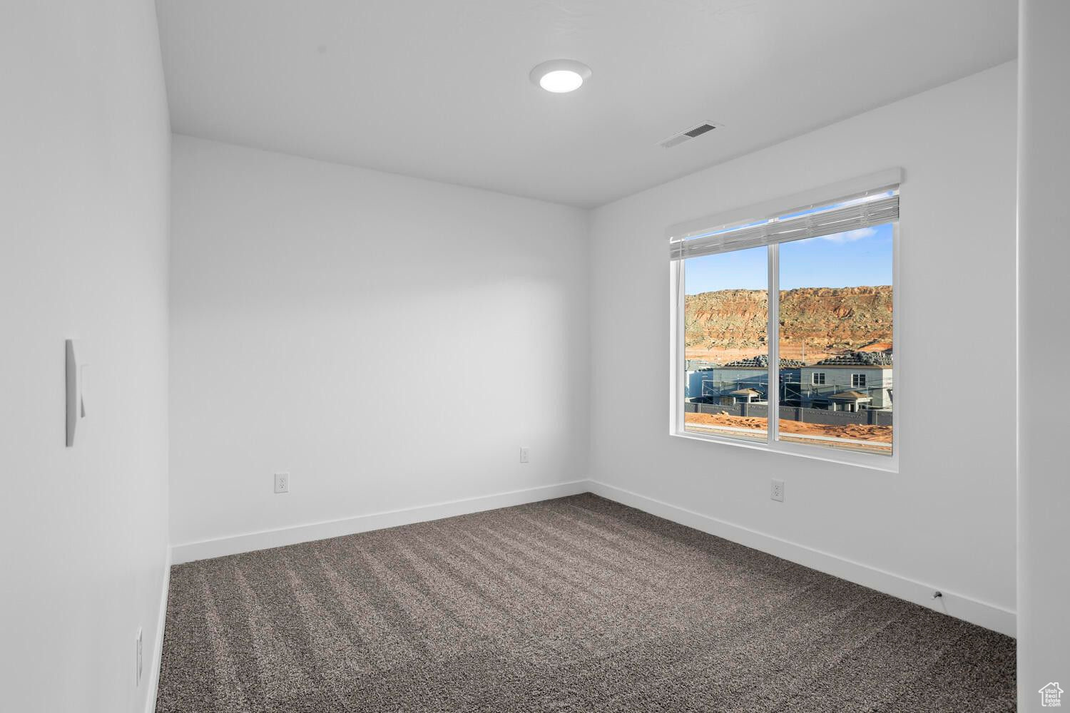 Empty room with baseboards, visible vents, and dark colored carpet