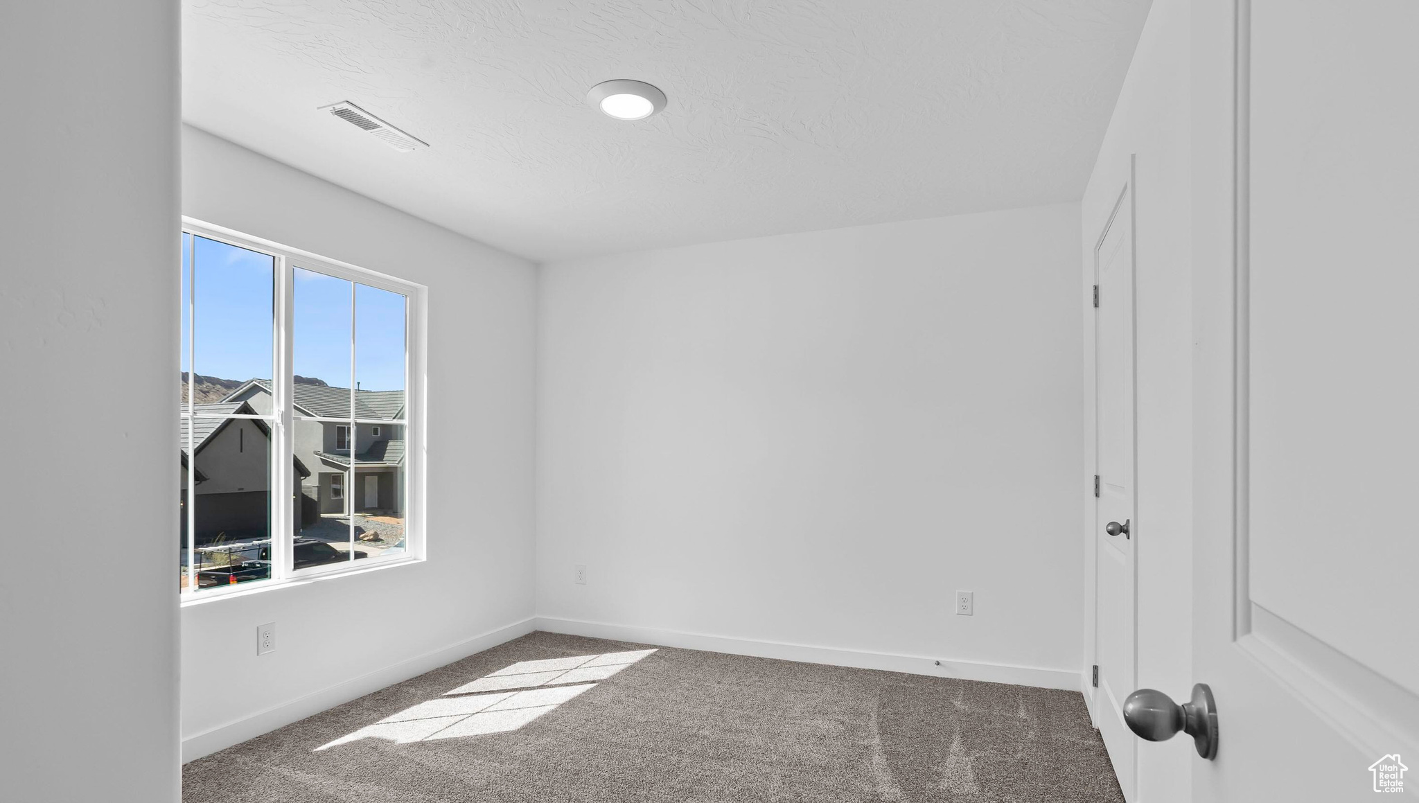 Carpeted empty room featuring baseboards and a textured ceiling