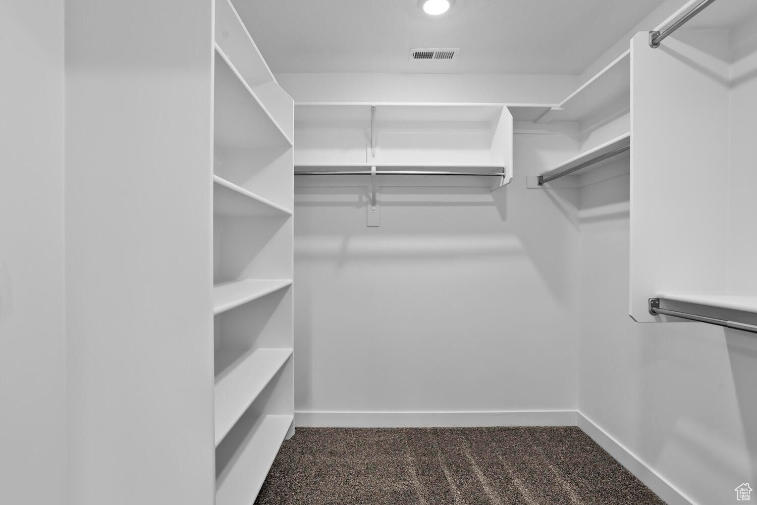 Spacious closet featuring dark colored carpet and visible vents