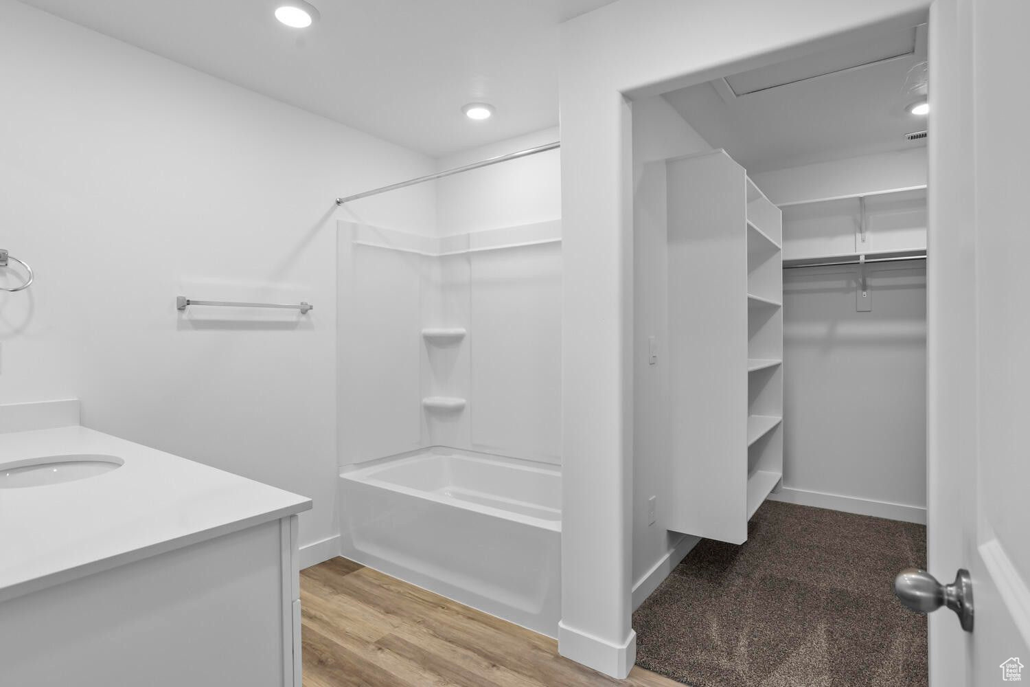 Full bathroom with a walk in closet, washtub / shower combination, recessed lighting, wood finished floors, and vanity