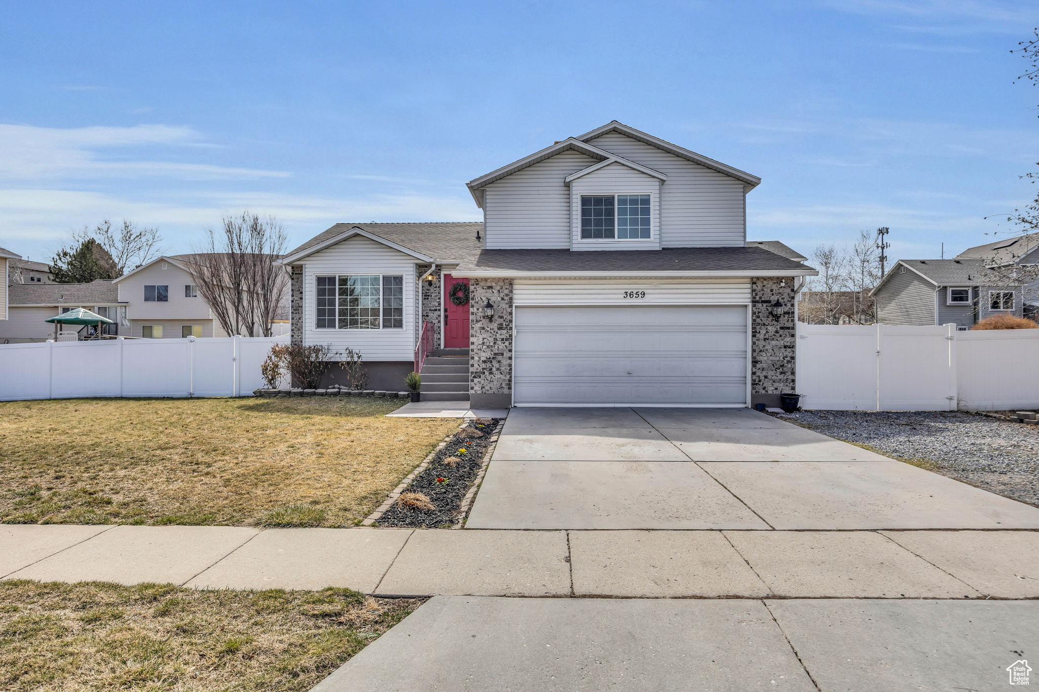 View of front of home featuring driveway, an attached garage, a front yard, and fence