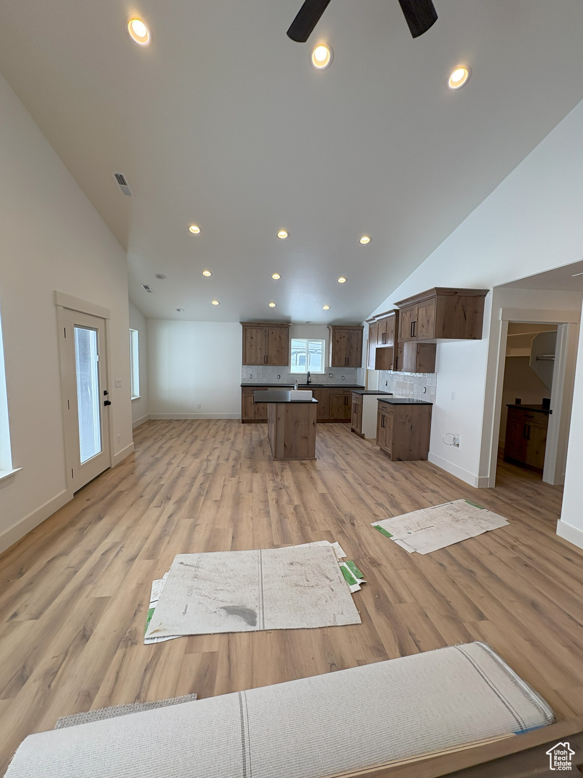 Unfurnished living room featuring recessed lighting, baseboards, light wood-style flooring, and lofted ceiling