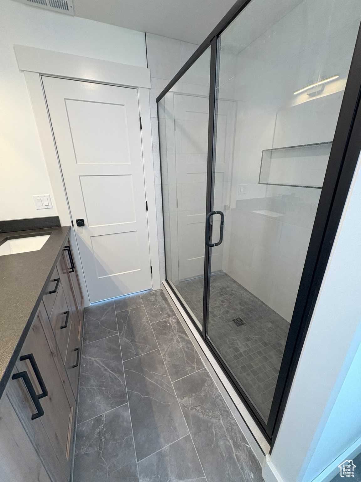 Full bath featuring visible vents, marble finish floor, a stall shower, and vanity