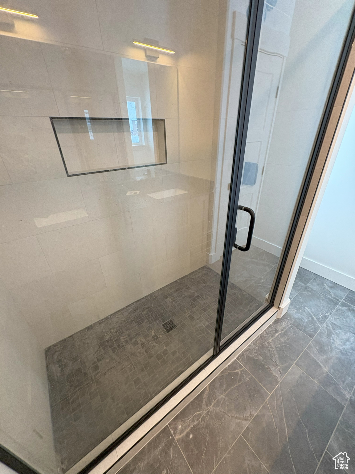 Bathroom with a shower stall and marble finish floor