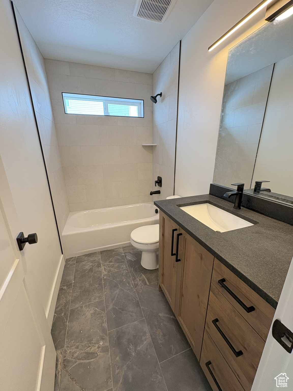 Bathroom featuring visible vents, toilet, marble finish floor, bathtub / shower combination, and vanity