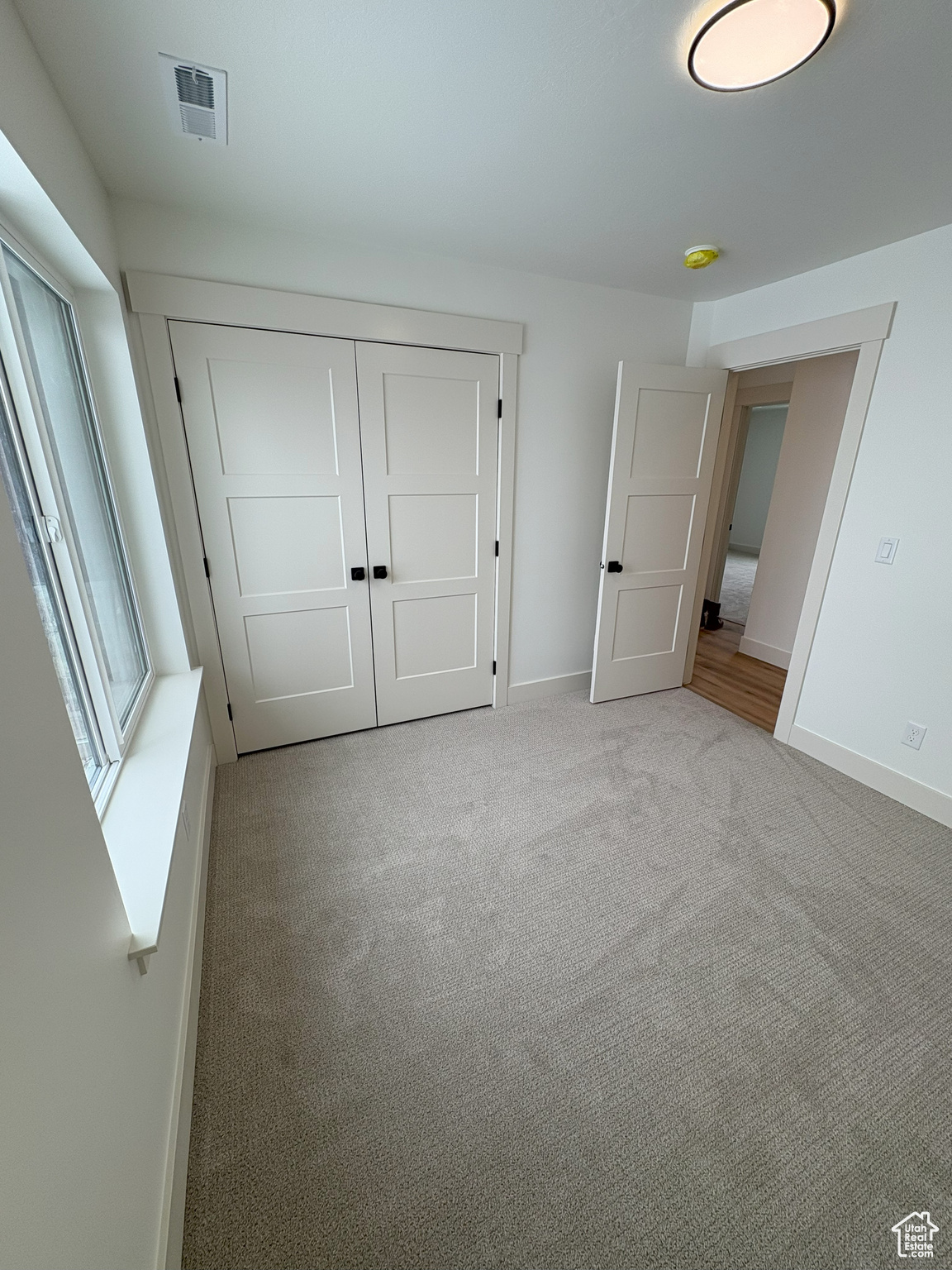 Unfurnished bedroom with visible vents, carpet, baseboards, and a closet