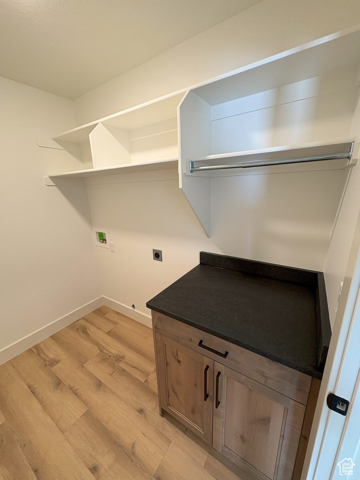 Laundry area featuring electric dryer hookup, light wood-type flooring, washer hookup, baseboards, and laundry area